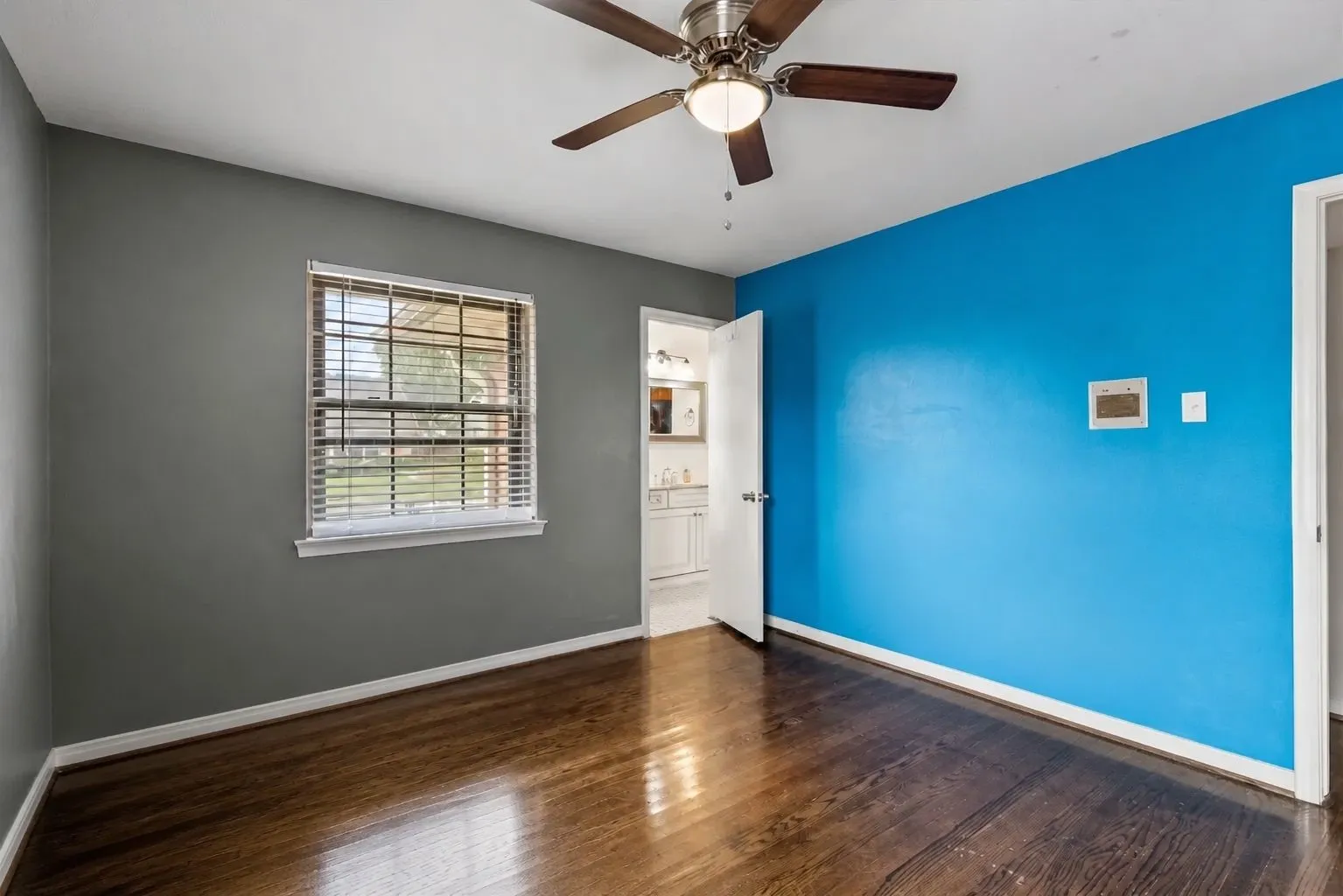 Bedroom featuring wood-finish flooring, a window with horizontal blinds, and a ceiling fan with integrated lighting. Furniture removed by AI.