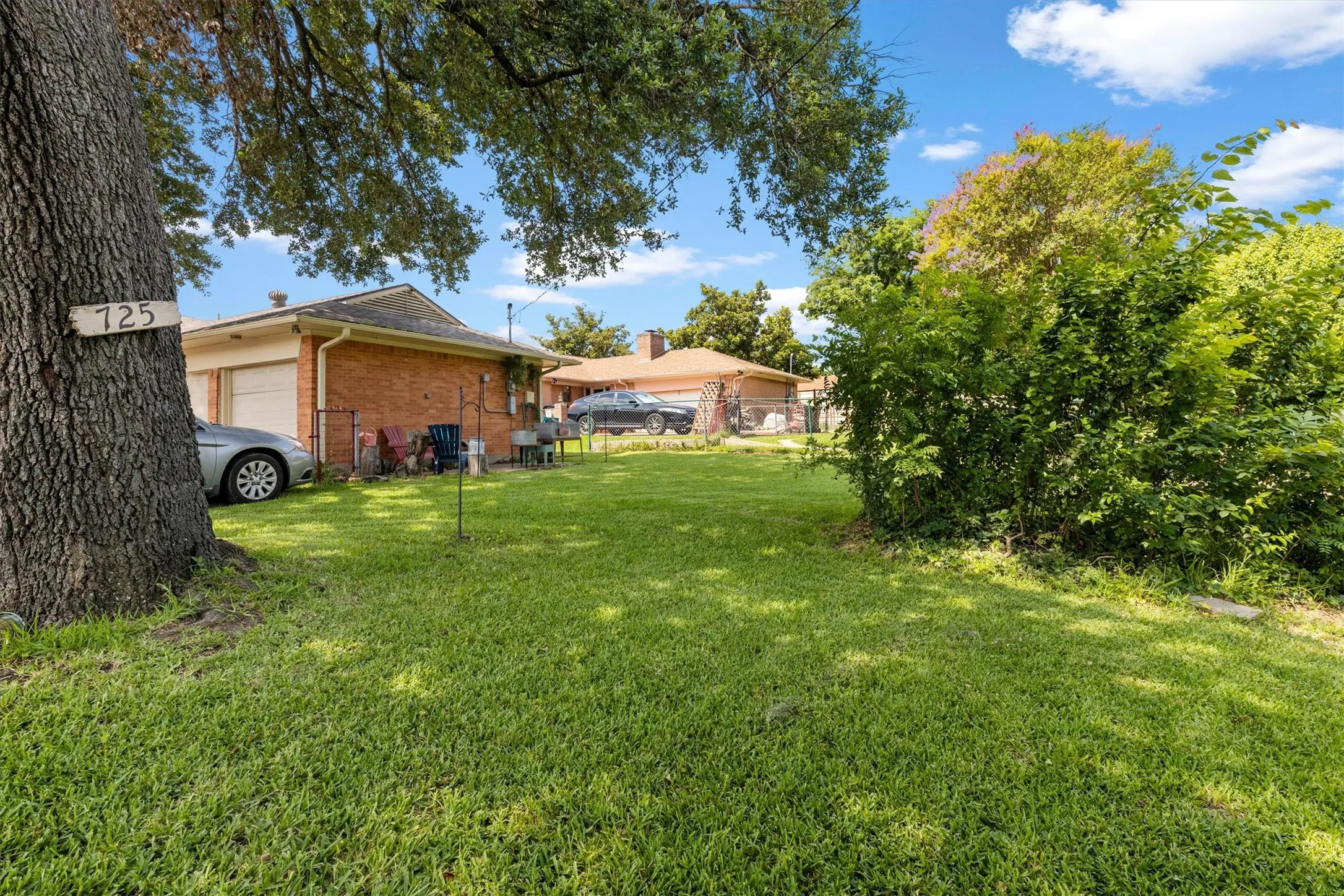 Spacious green lawn with mature trees and established perimeter plantings