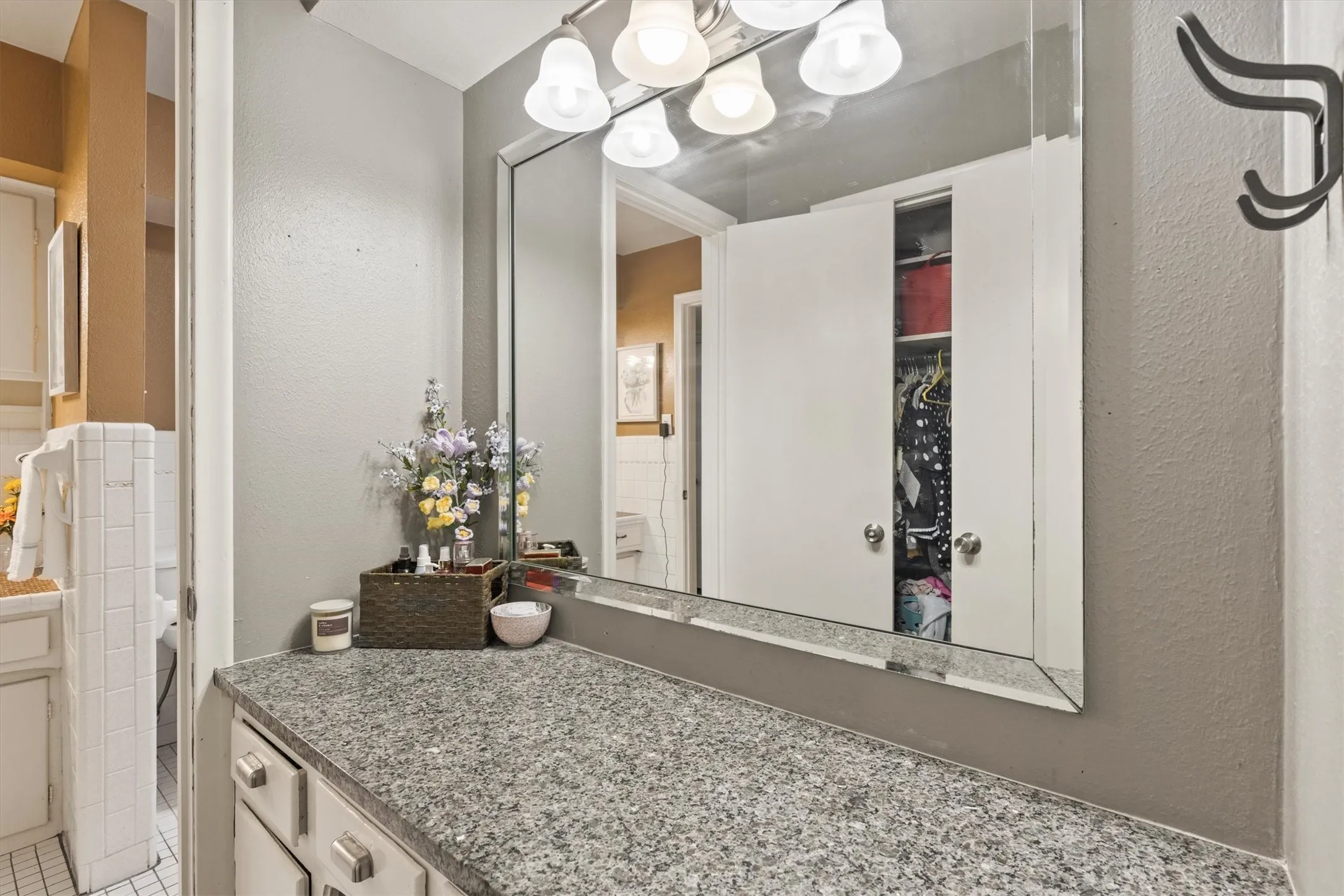 Bathroom vanity featuring a granite countertop, a large framed mirror, and a three-light vanity fixture
