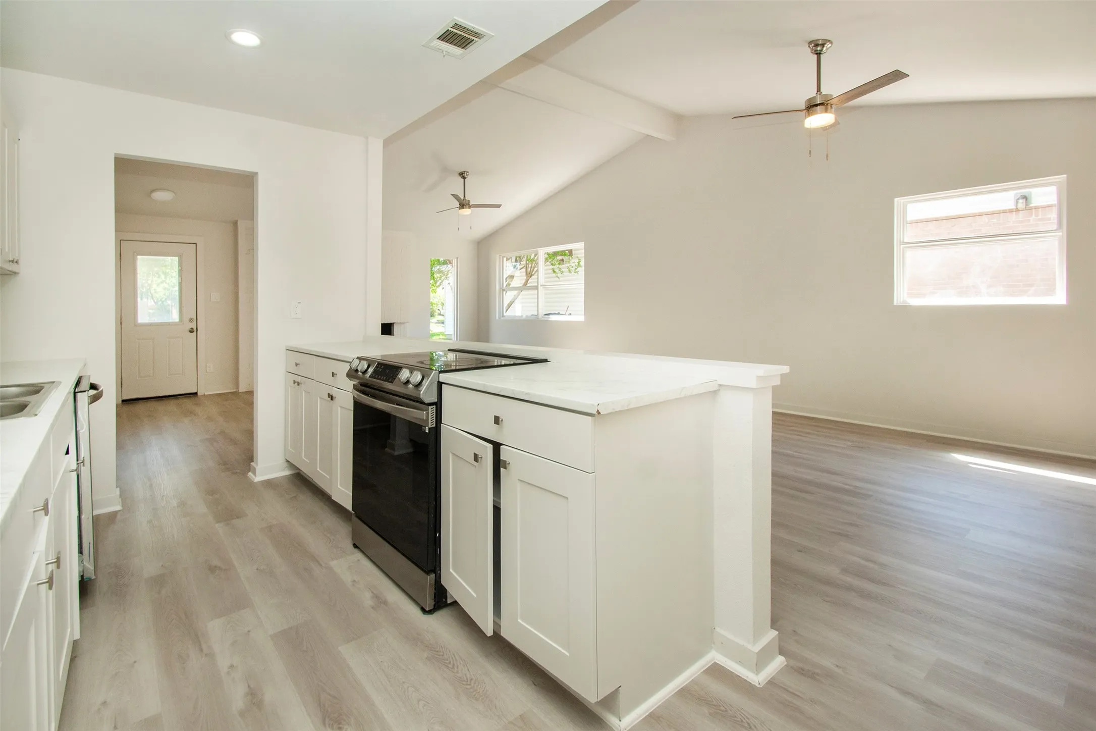Kitchen with light hardwood / wood-style floors, white cabinets, ceiling fan, and stainless steel electric range