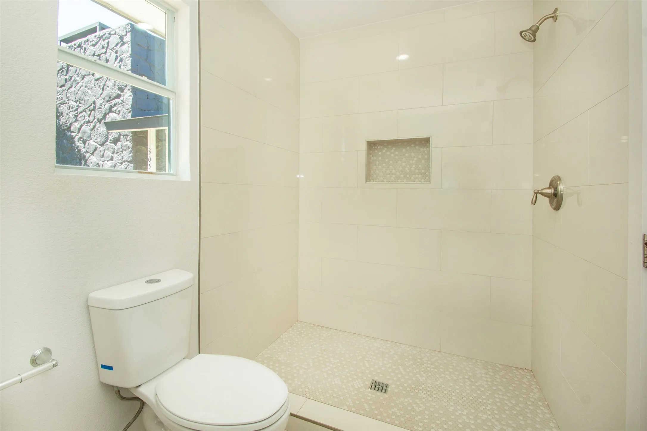 Bathroom featuring tiled shower and toilet