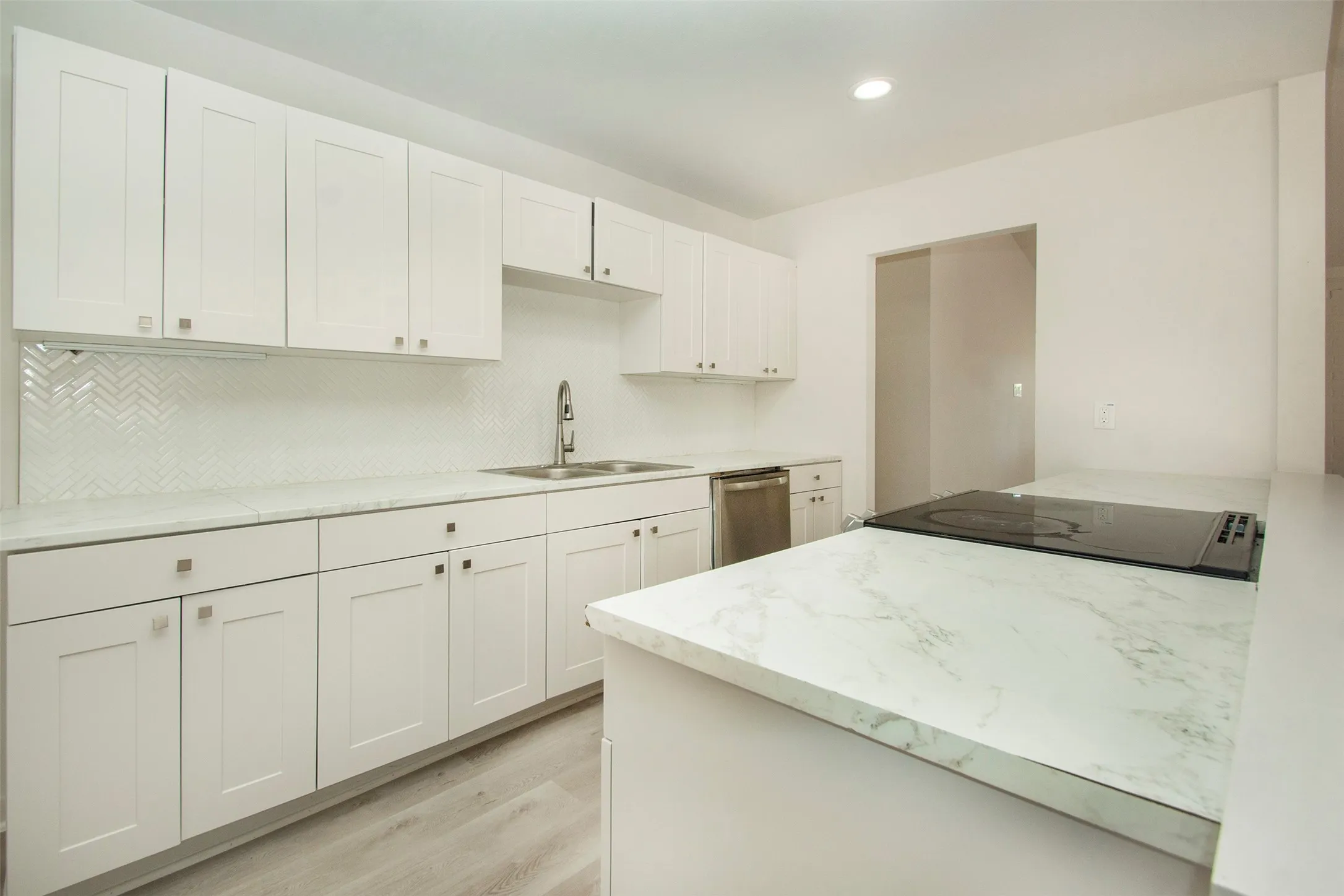 Kitchen with white cabinetry, stainless steel dishwasher, sink, tasteful backsplash, and light hardwood / wood-style floors