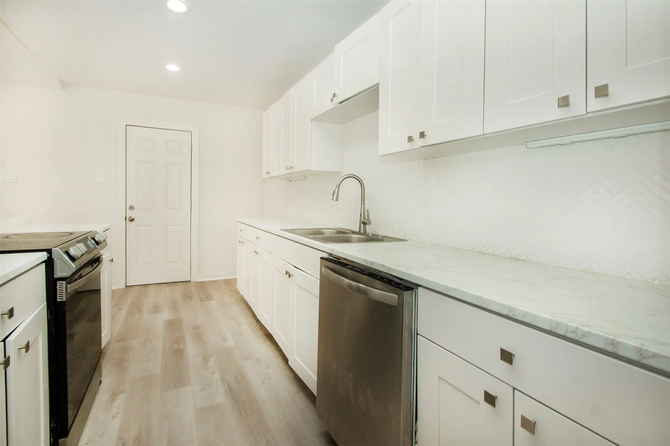 Kitchen with electric stove, white cabinets, sink, dishwasher, and light wood-type flooring
