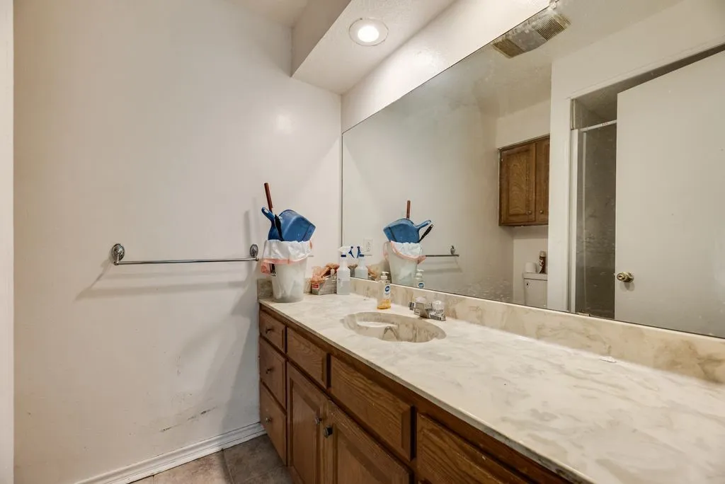 Bathroom vanity featuring a light-toned stone countertop, integrated sink, and wood-finish cabinetry