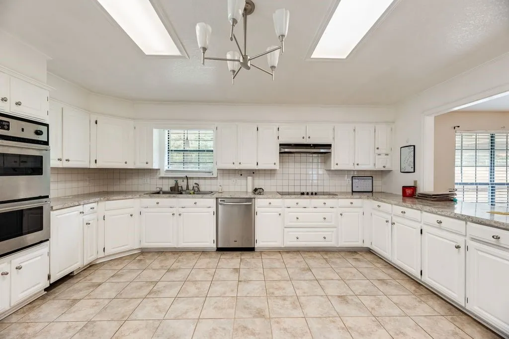 Spacious kitchen featuring extensive white cabinetry, a double wall oven, a built-in cooktop, and a tile backsplash