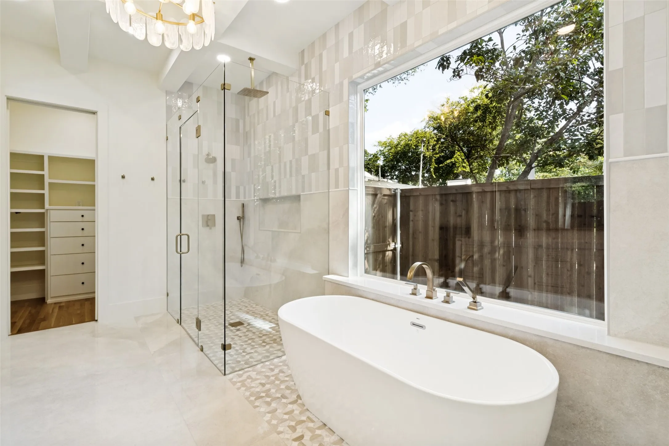 Freestanding soaking tub with brushed brass fixtures, complemented by a large picture window