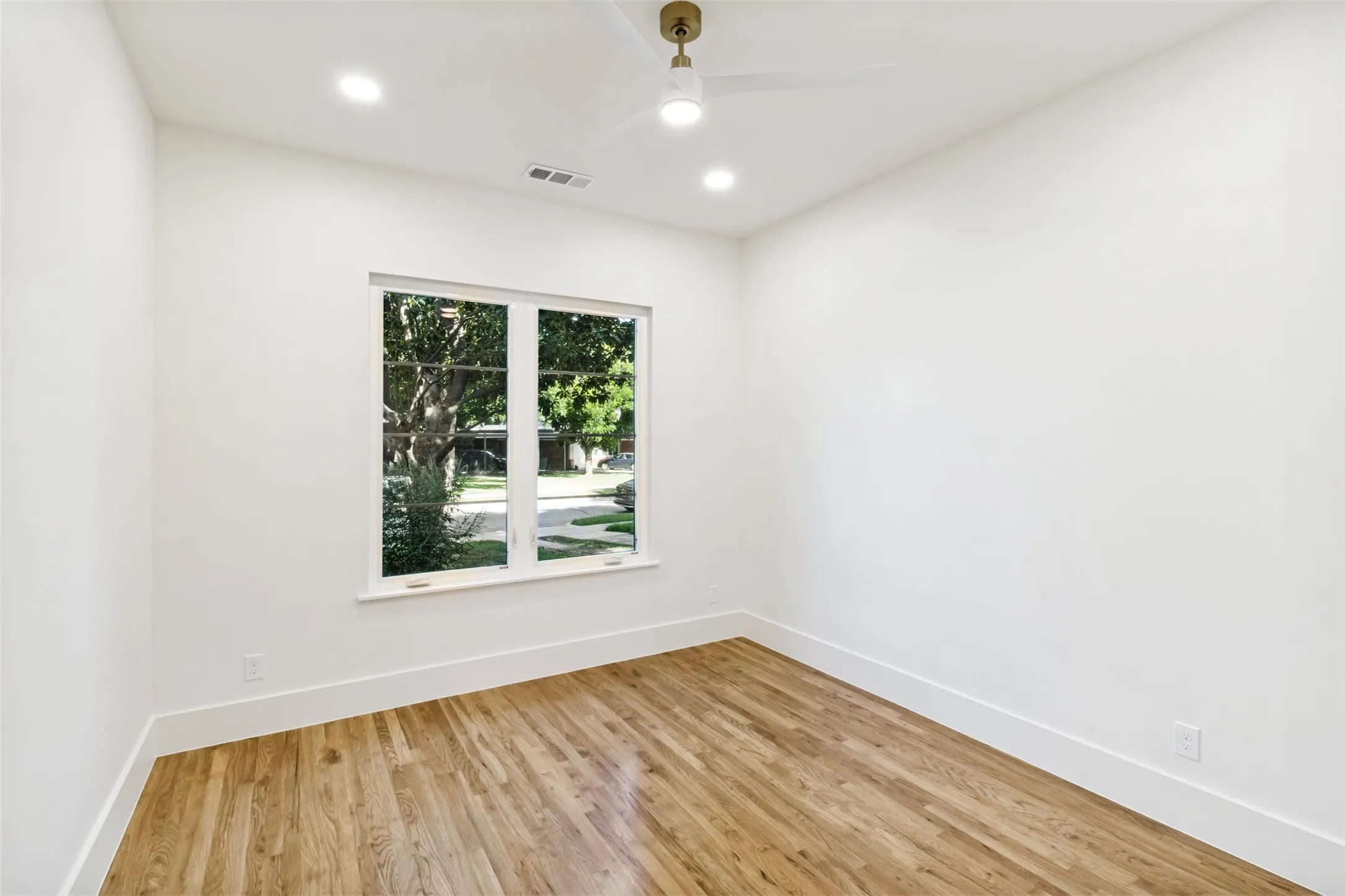 Bright interior space featuring a double window, wood-finish flooring, recessed lighting, a ceiling fan with integrated light, and crisp white walls with baseboards