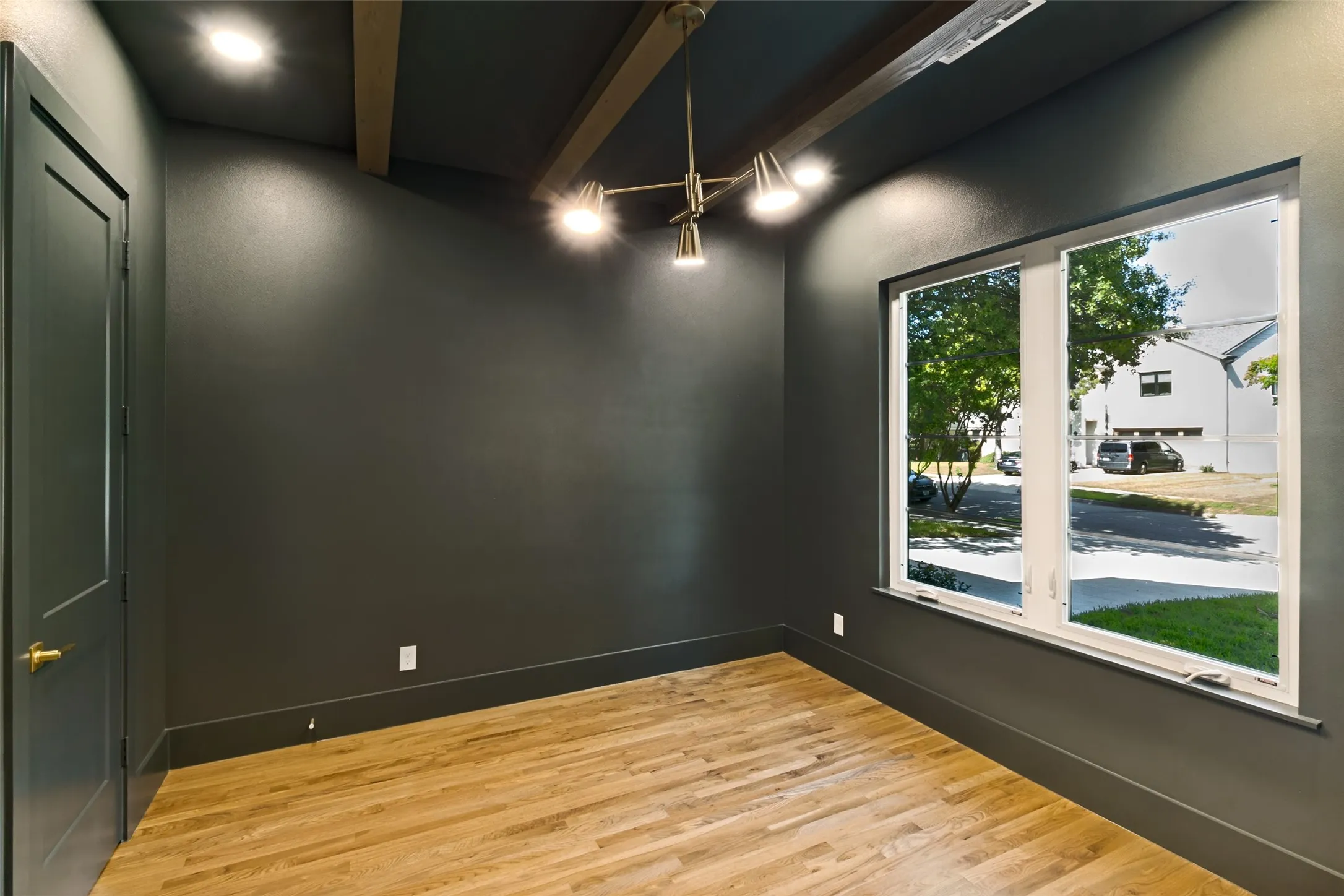 Interior space featuring wood-finish flooring, a large window, a modern ceiling light fixture, exposed ceiling beams, and recessed lighting