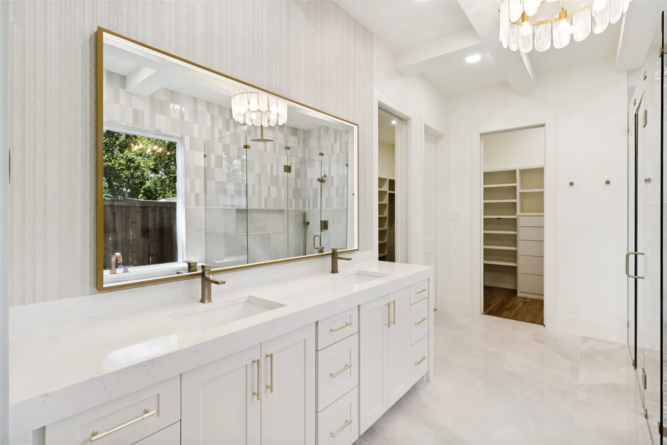 Dual vanity with white cabinetry, gold-toned hardware, and integrated sinks