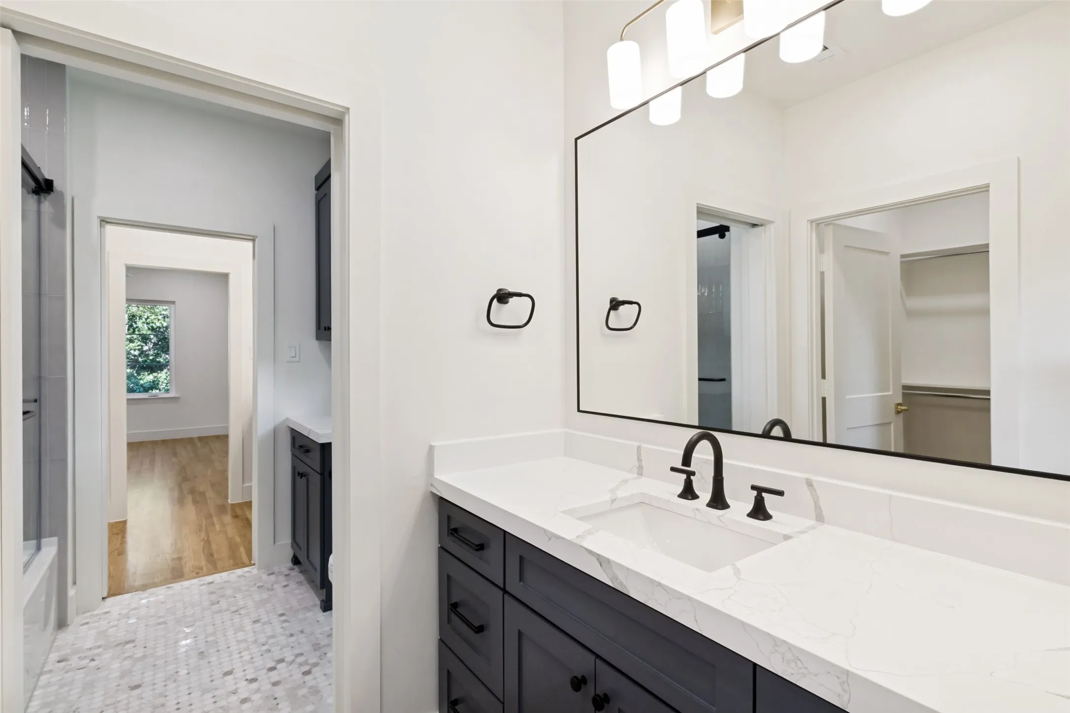Bathroom featuring a dark wood-finish vanity with white countertop, integrated sink, and matte black fixtures