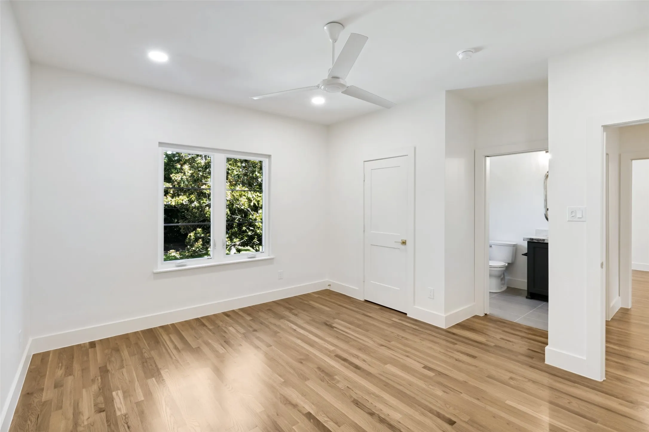 Spacious room featuring wood-finish flooring, recessed lighting, and a contemporary ceiling fan