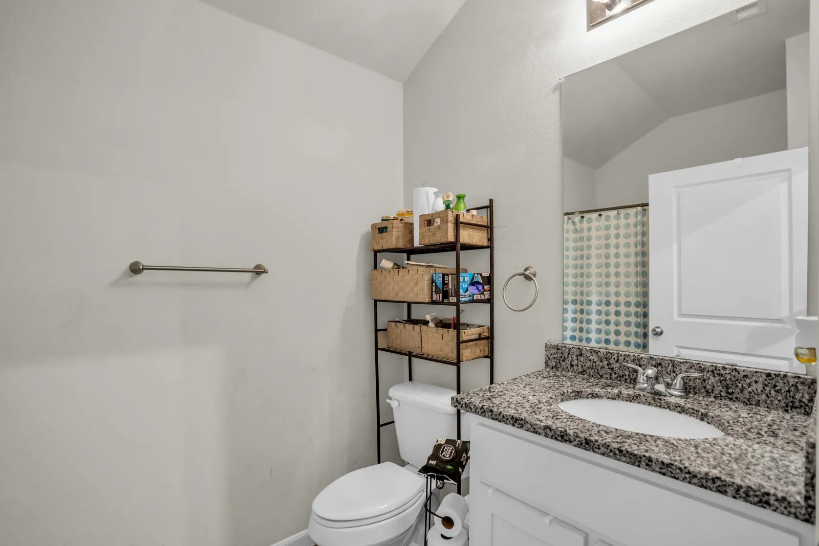 Bathroom featuring a vanity with a granite-style countertop, integrated sink, and white cabinetry