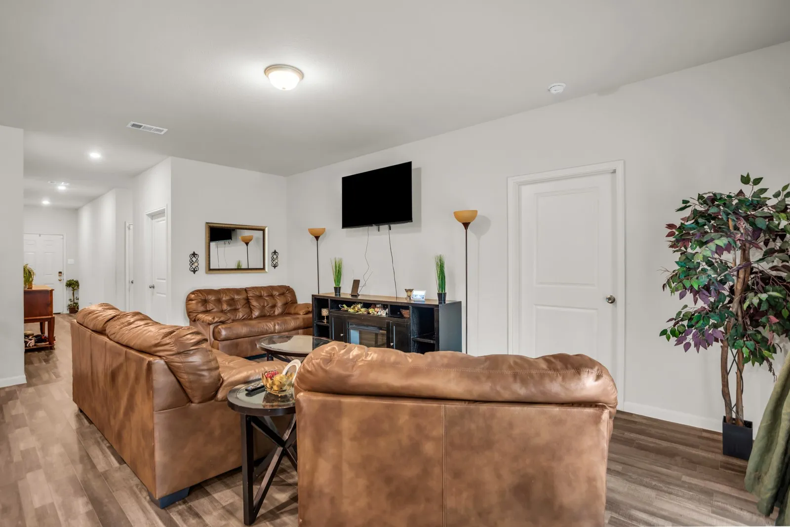 Spacious living area featuring wood-finish flooring, white walls, and a recessed ceiling light