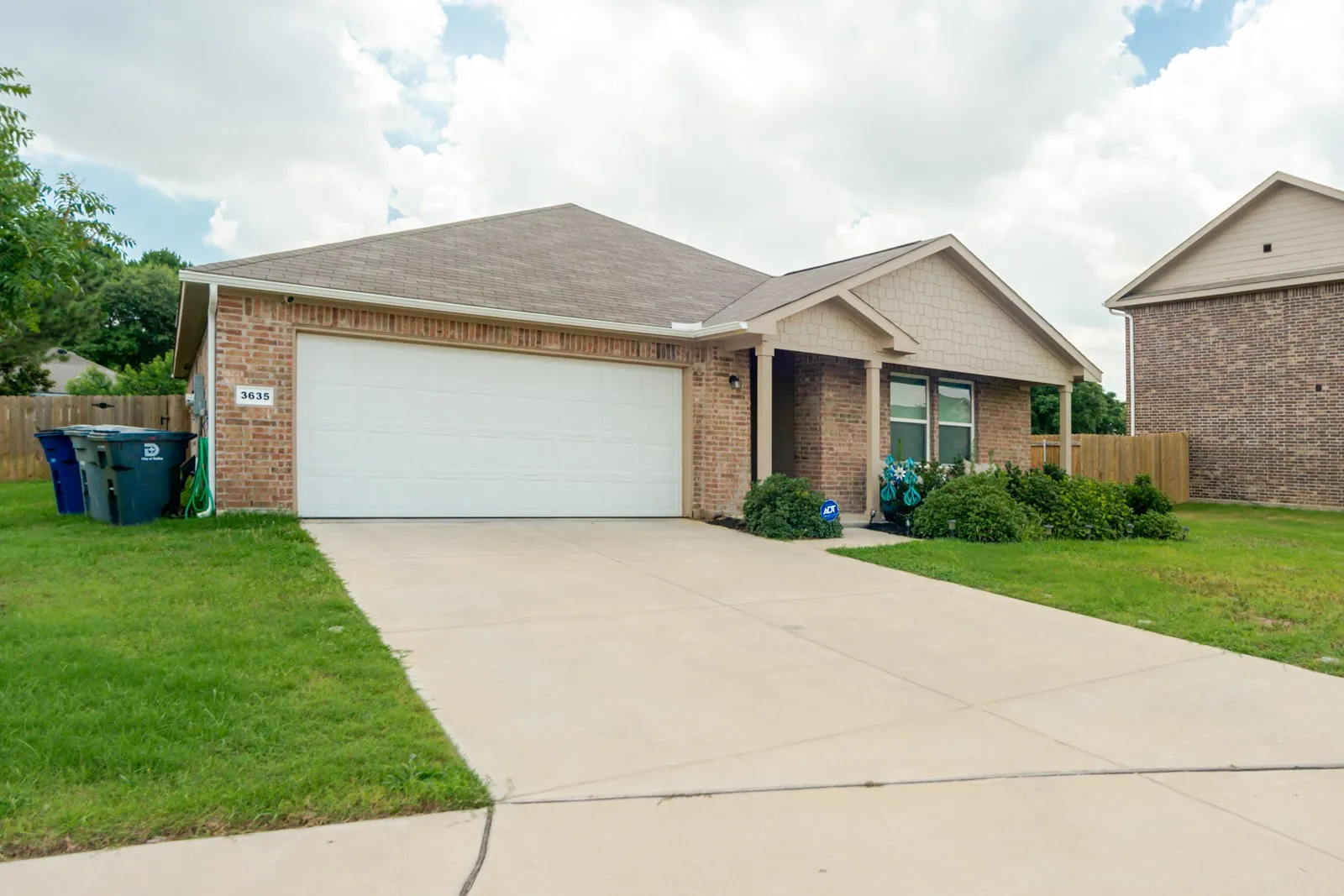 Brick exterior residence featuring a two-car garage, a concrete driveway, and a covered entry