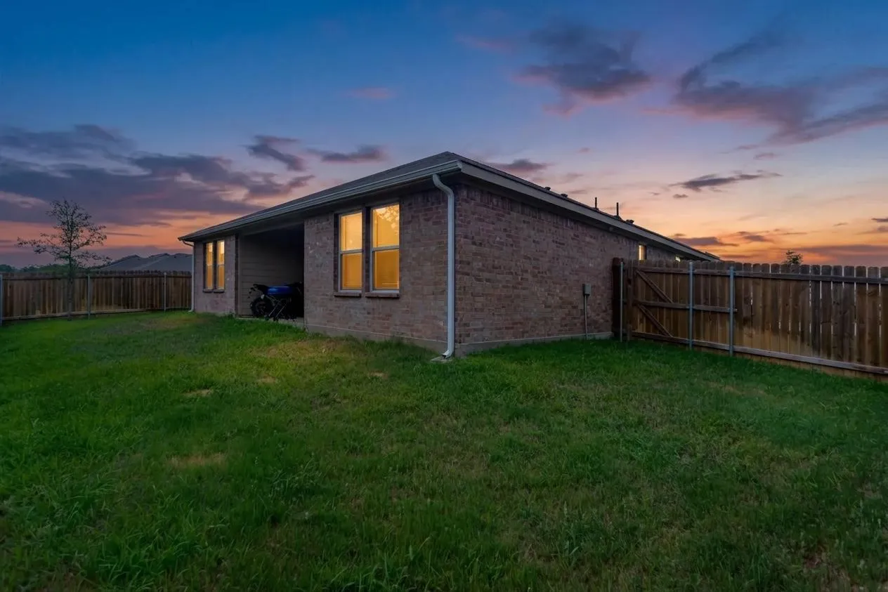 Expansive rear yard featuring a privacy fence, a brick exterior, an covered patio, and multiple windows