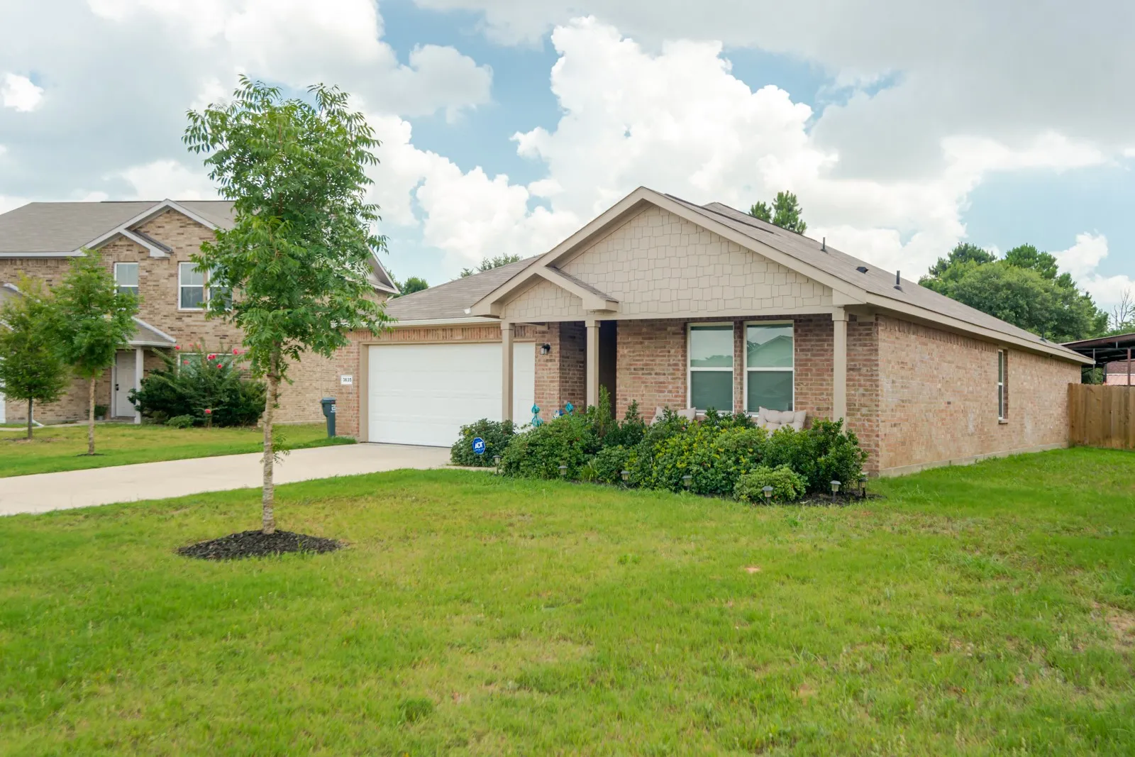 Single-story brick exterior with a front-facing garage, covered entry porch, and a gable roofline featuring shake siding