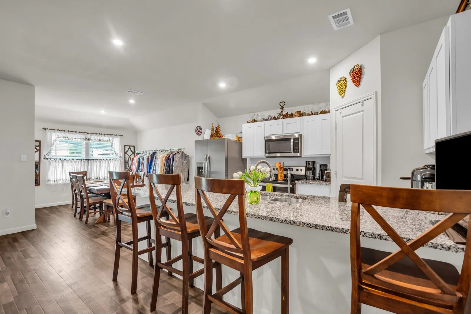 Open-concept kitchen with a granite countertop island, stainless steel microwave, and white cabinetry