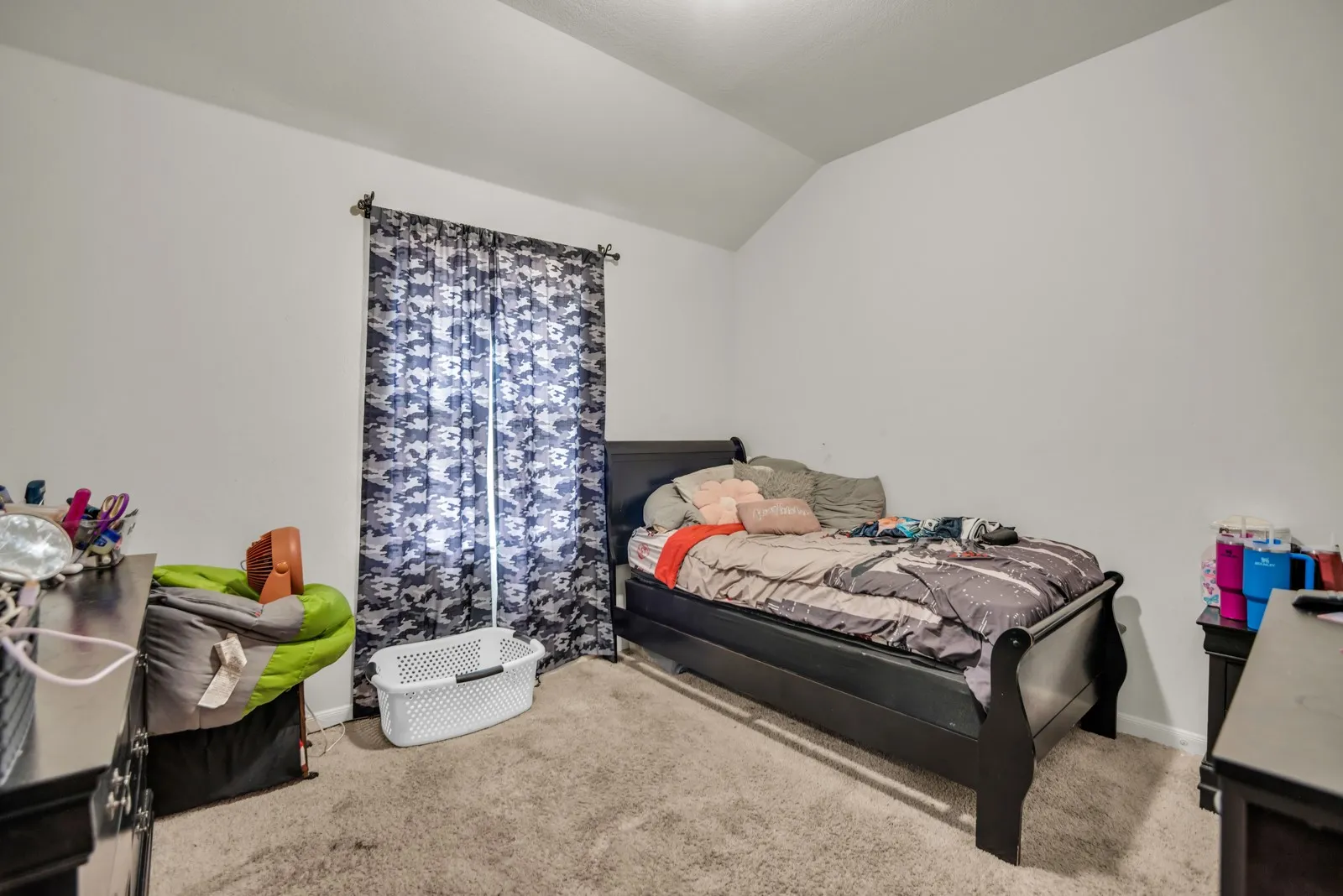 Wall-to-wall carpeted room with neutral paint, a window with curtains, and a ceiling with a sloped section