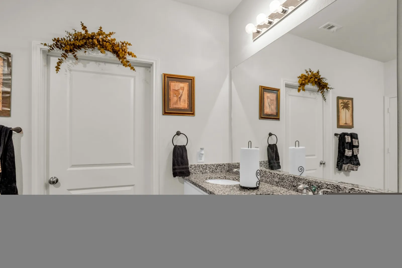Spacious vanity area featuring an expansive mirror, dual undermount sinks, and a speckled countertop