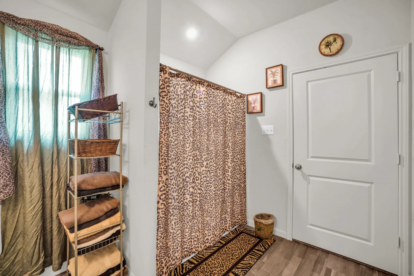 Bathroom featuring wood-finish flooring, a two-panel interior door, and a shower area with a ceiling-mounted light fixture