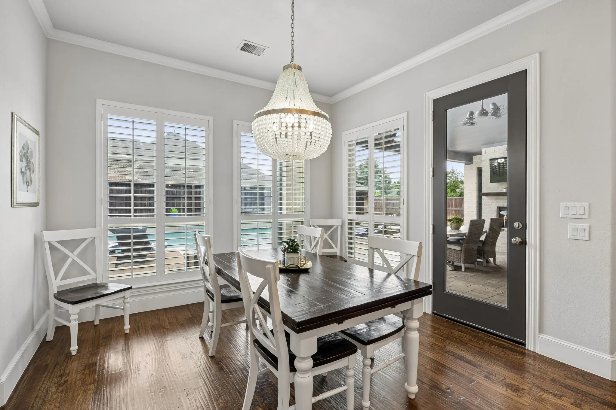 Casual Dining leads to the Large Covered Patio with wood burning fireplace.  Another designer Chandelier here.  Beautiful crown molding, shutters and extended baseboards.  A true custom home throughout.