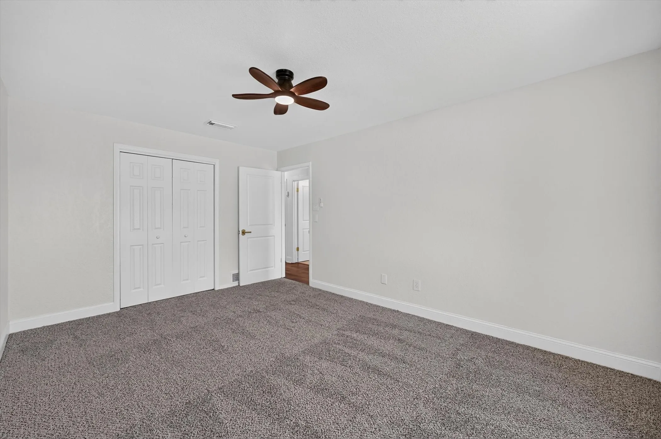 Spacious room featuring neutral carpeting, light gray wall paint, and white trim