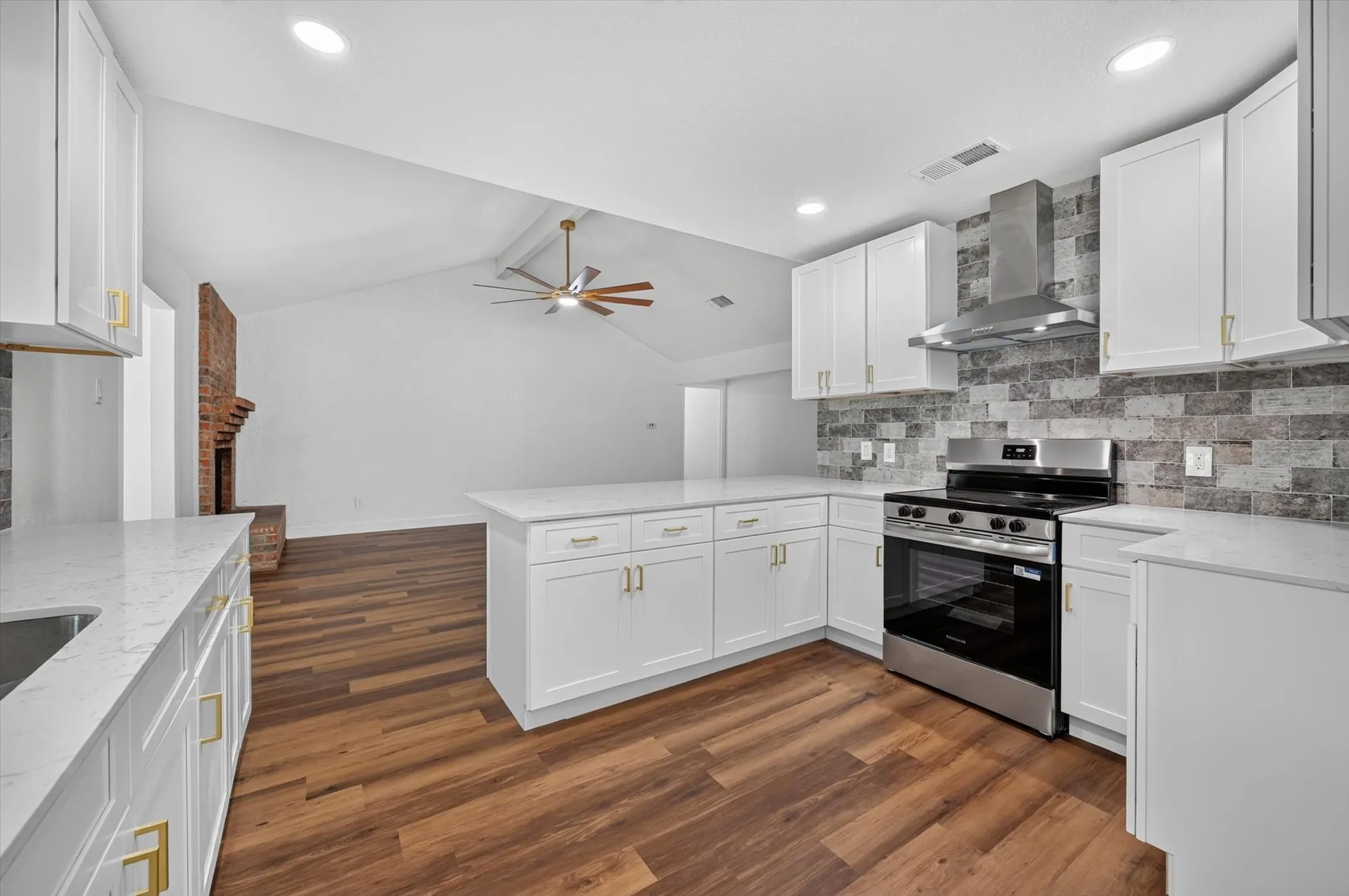 Modern kitchen featuring white cabinetry with gold-tone hardware, white countertops, and a full stainless steel appliance package