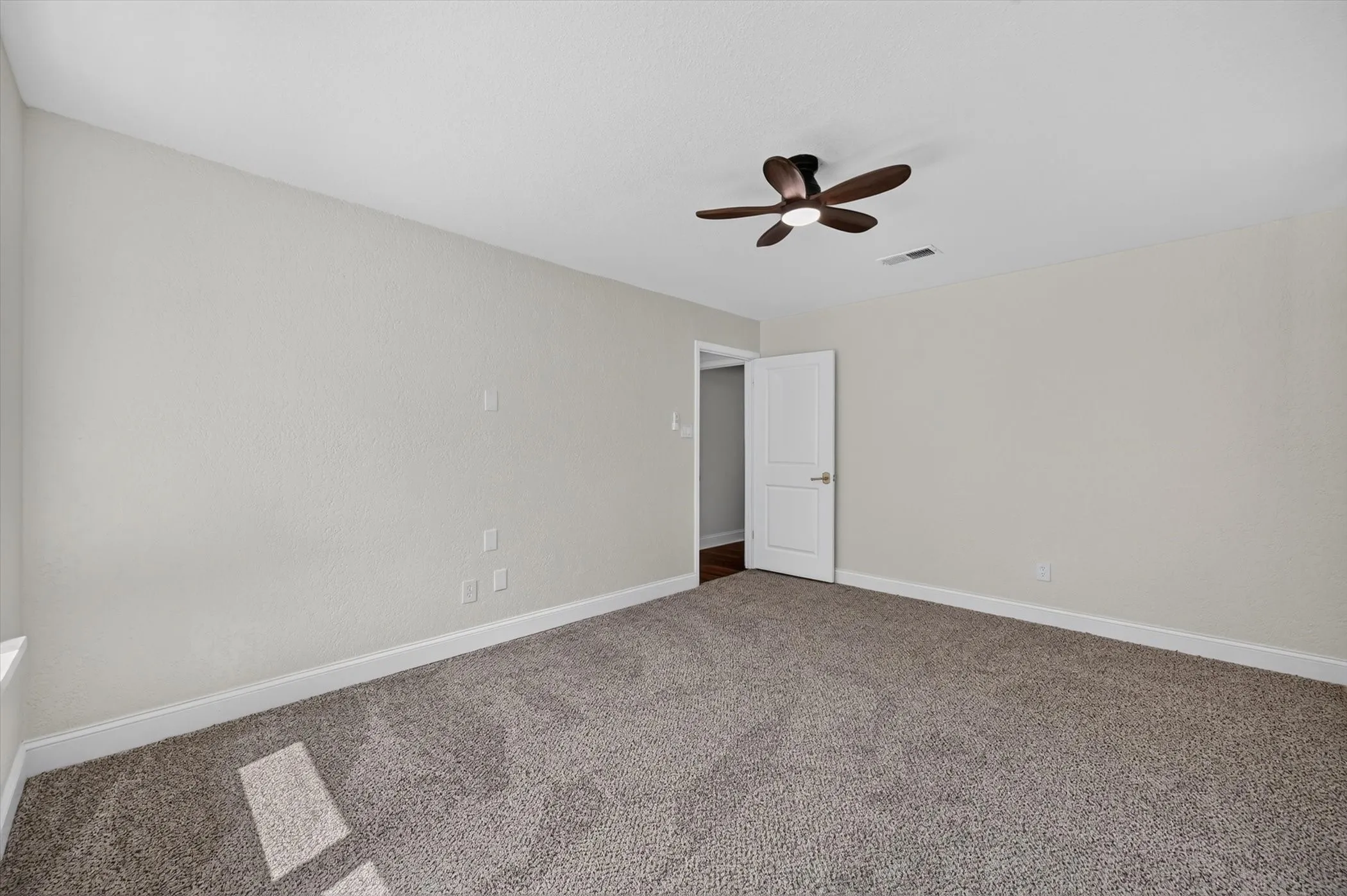 Carpeted room featuring light gray walls, a contemporary ceiling fan with integrated lighting, and white baseboards