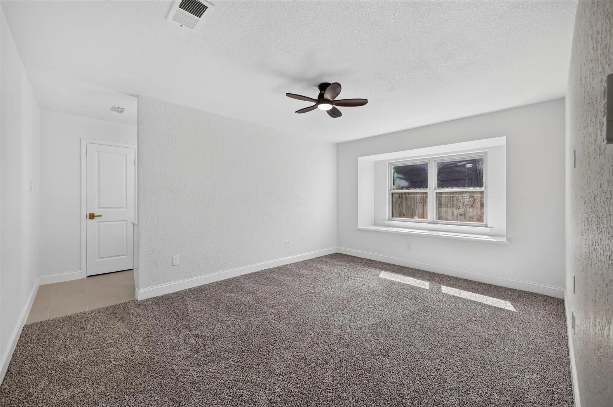 Bedroom featuring neutral-toned carpet, a window with a deep sill, and a ceiling fan