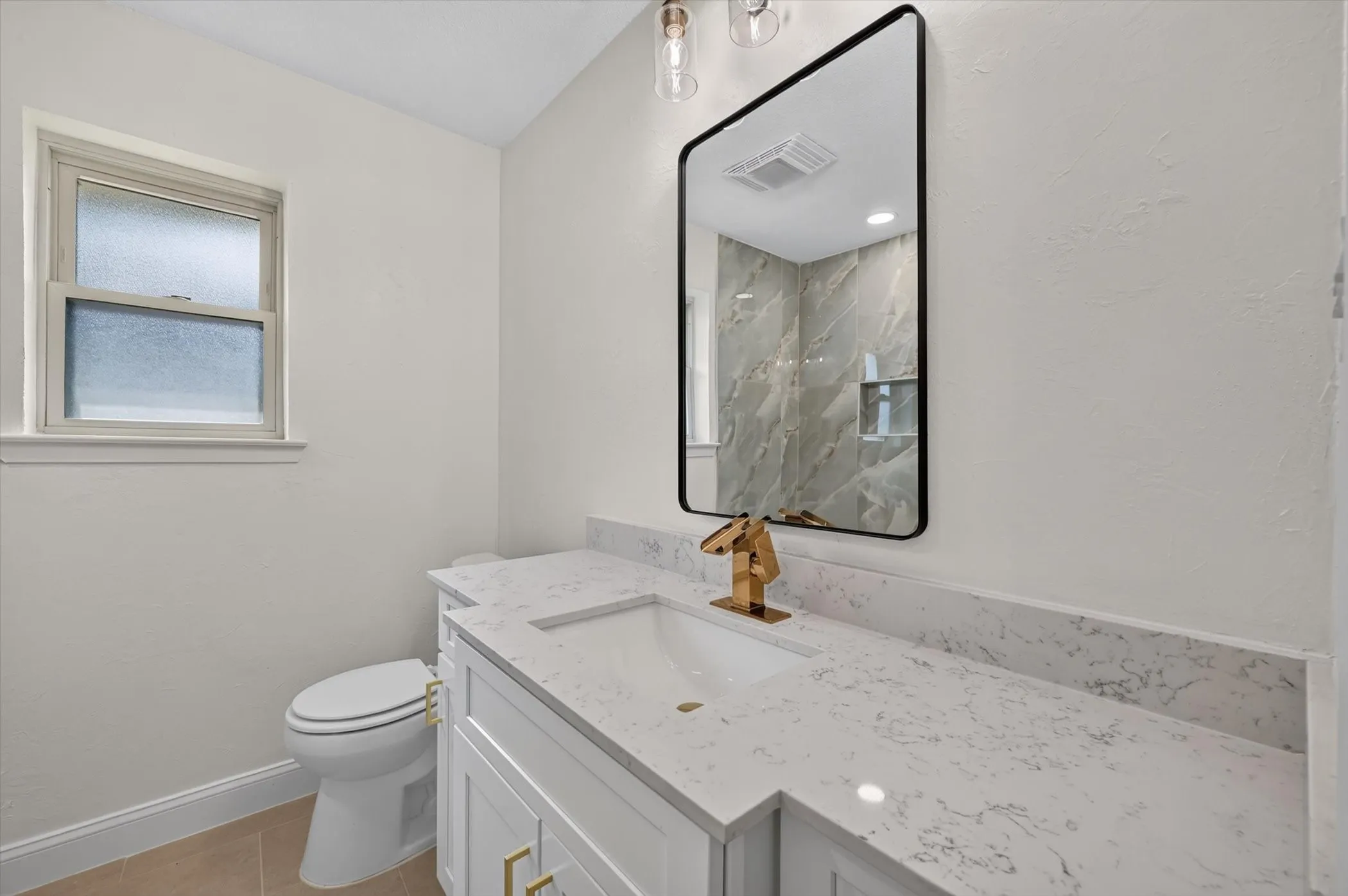 Bathroom vanity featuring a quartz countertop with an integrated sink, gold-finish faucet, and coordinating gold-tone cabinet hardware