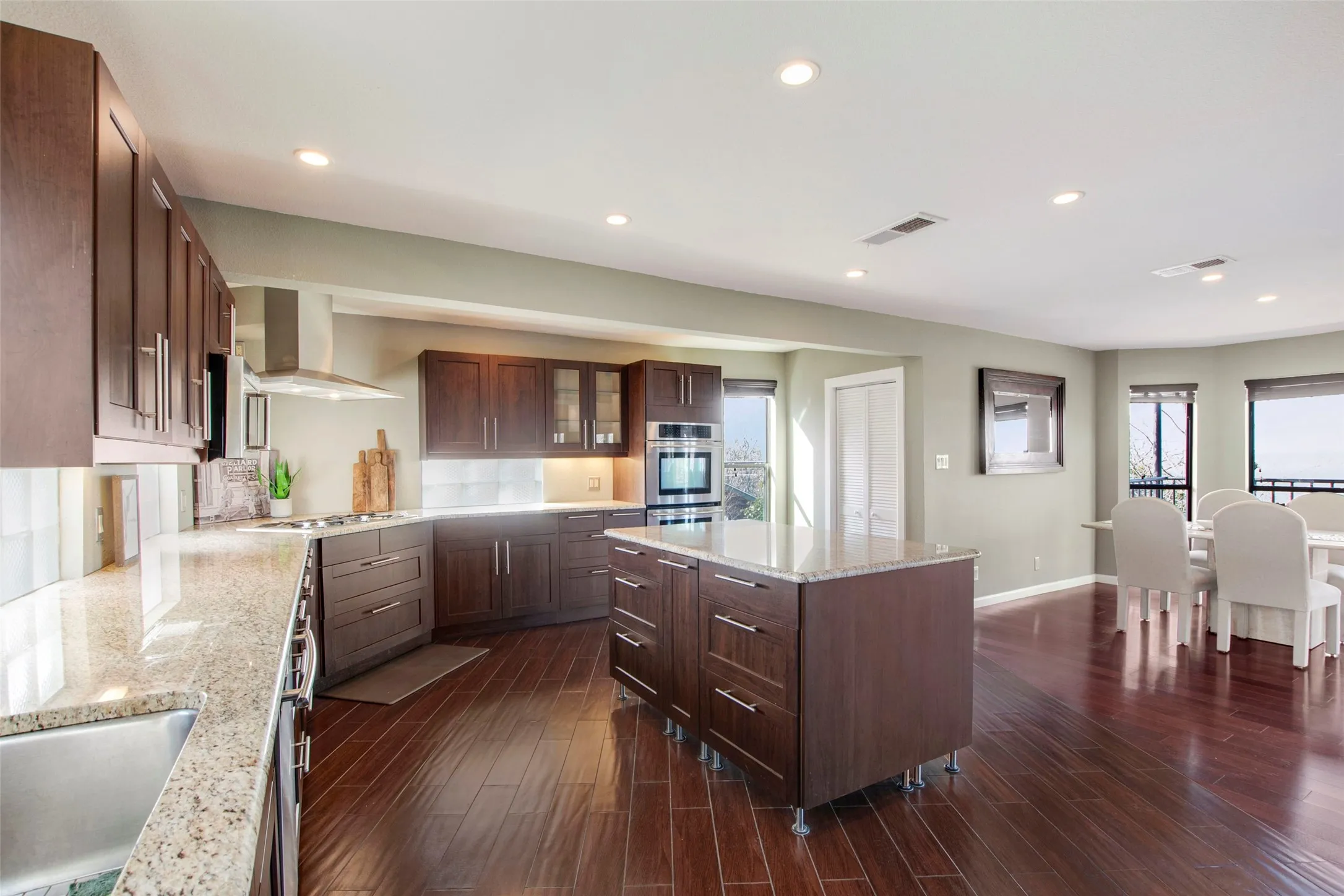 Spacious kitchen featuring dark wood cabinetry, light-toned countertops, and wood-finish flooring