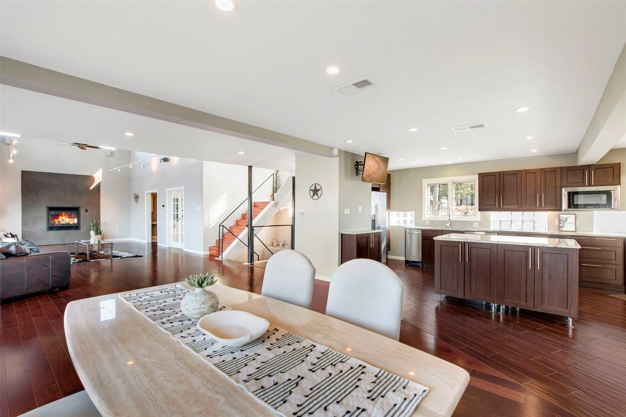 Open-concept living space featuring wood-finish flooring, a contemporary fireplace, and recessed lighting