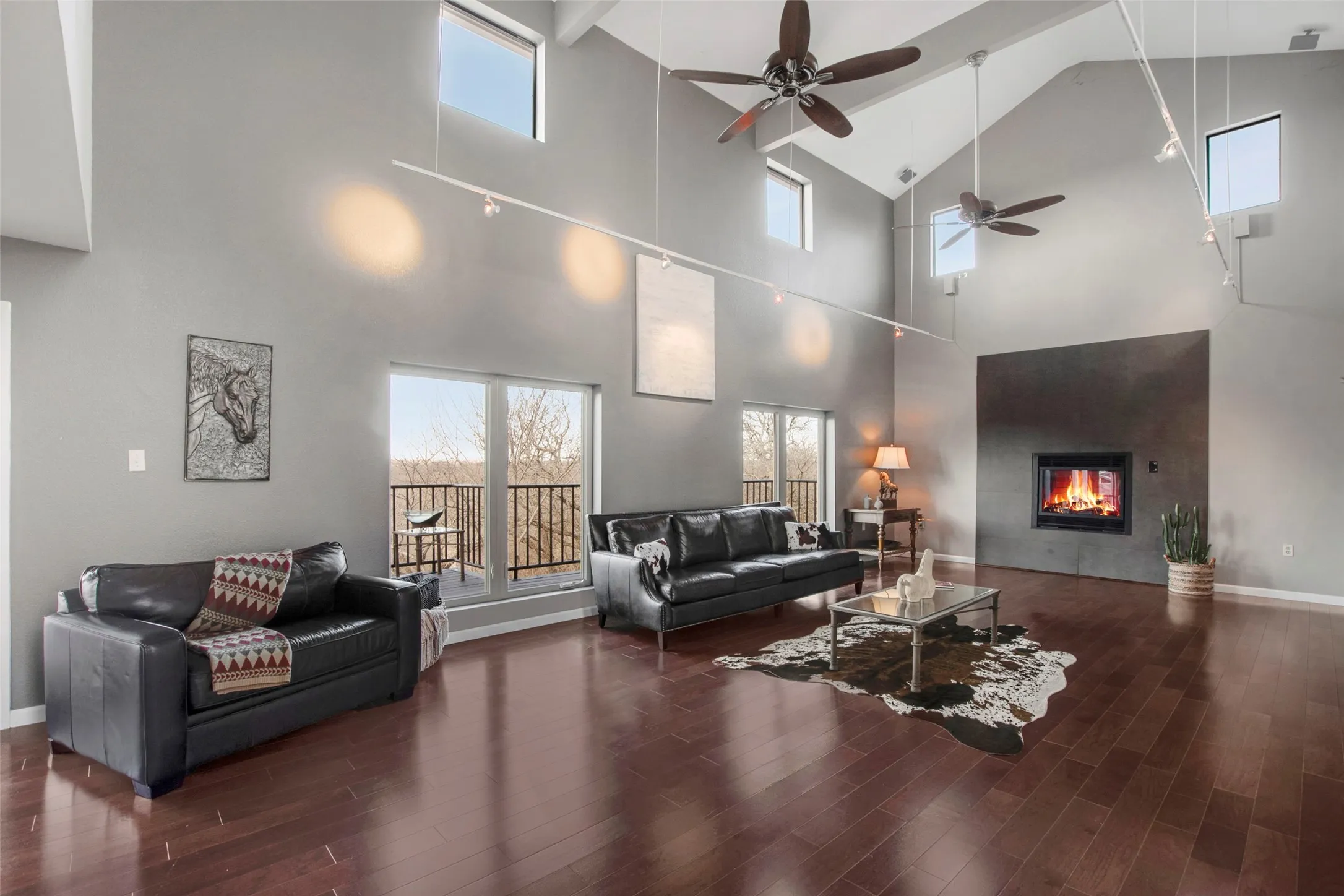 Spacious living area featuring vaulted ceilings, rich wood-finish flooring, and a contemporary fireplace