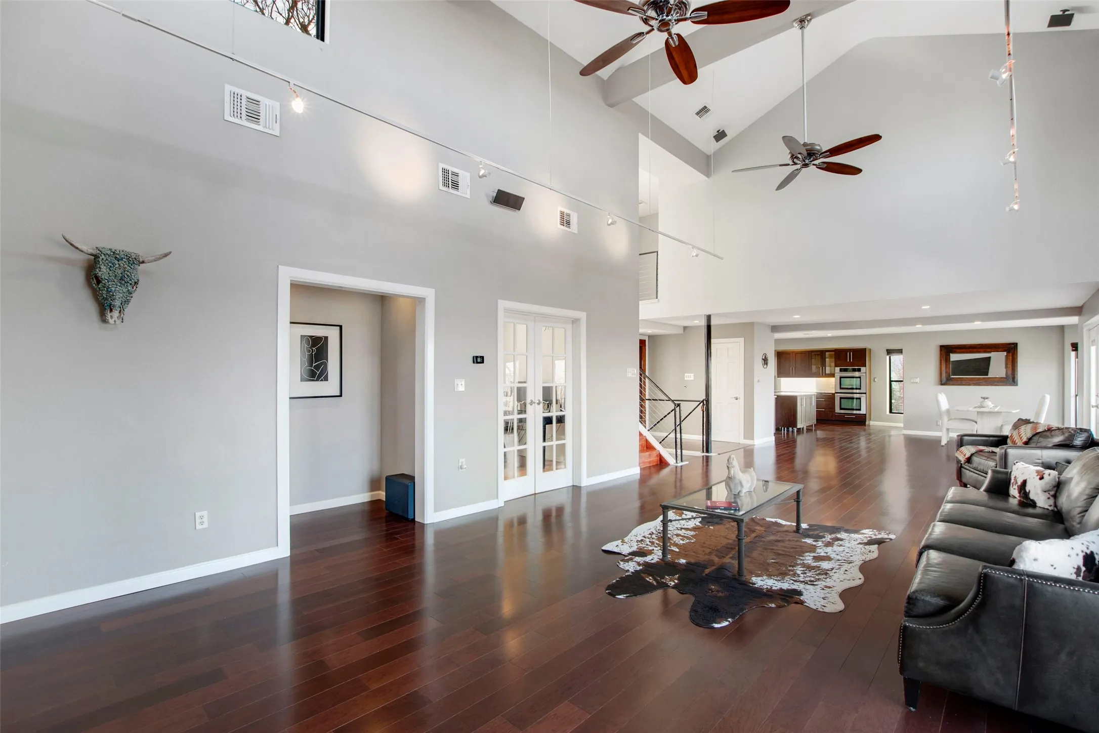 Spacious living area featuring high vaulted ceilings, rich wood-finish flooring, and multiple ceiling fans