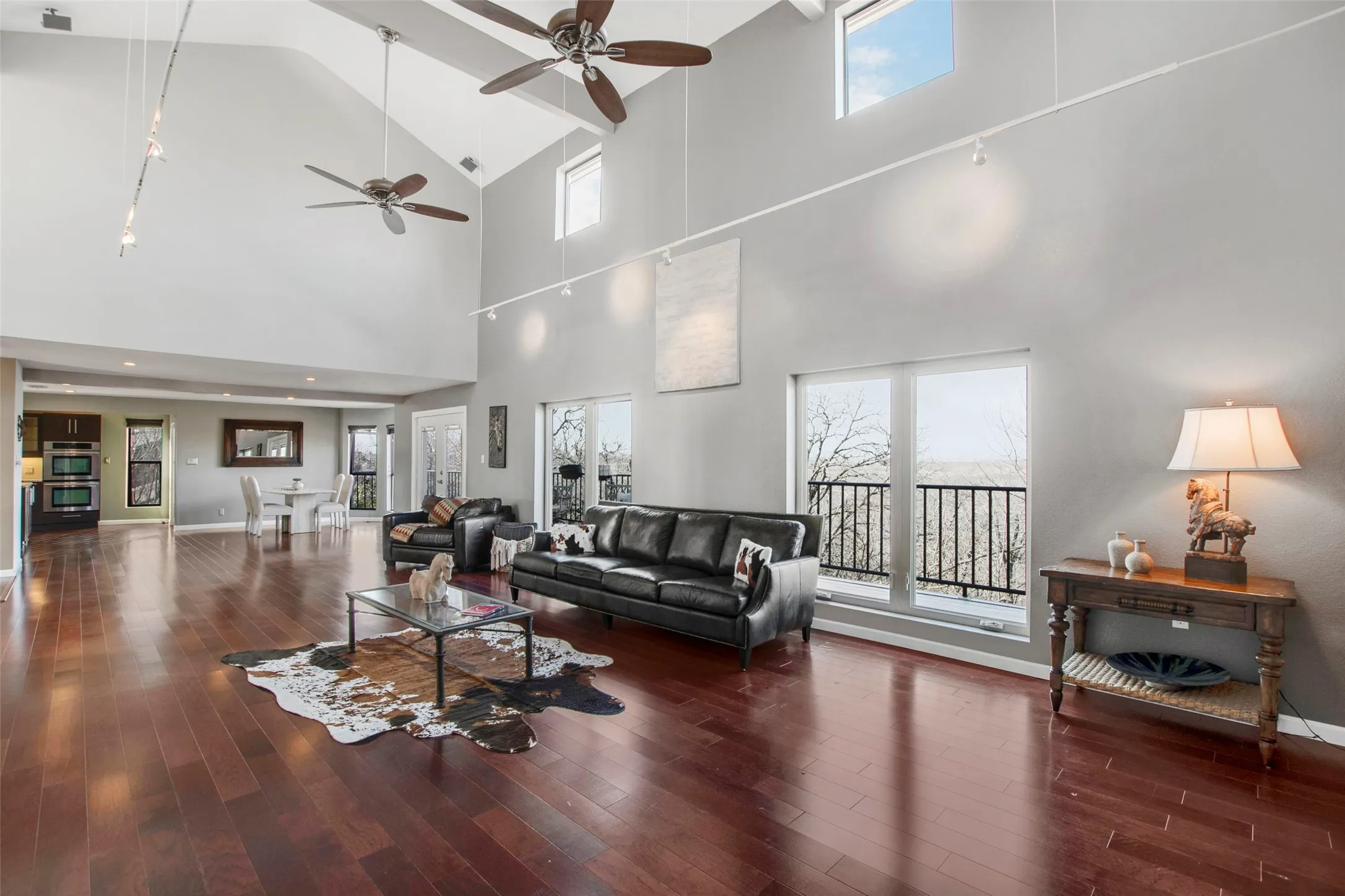 Spacious living area featuring high vaulted ceilings, multiple ceiling fans, and rich wood-finish flooring