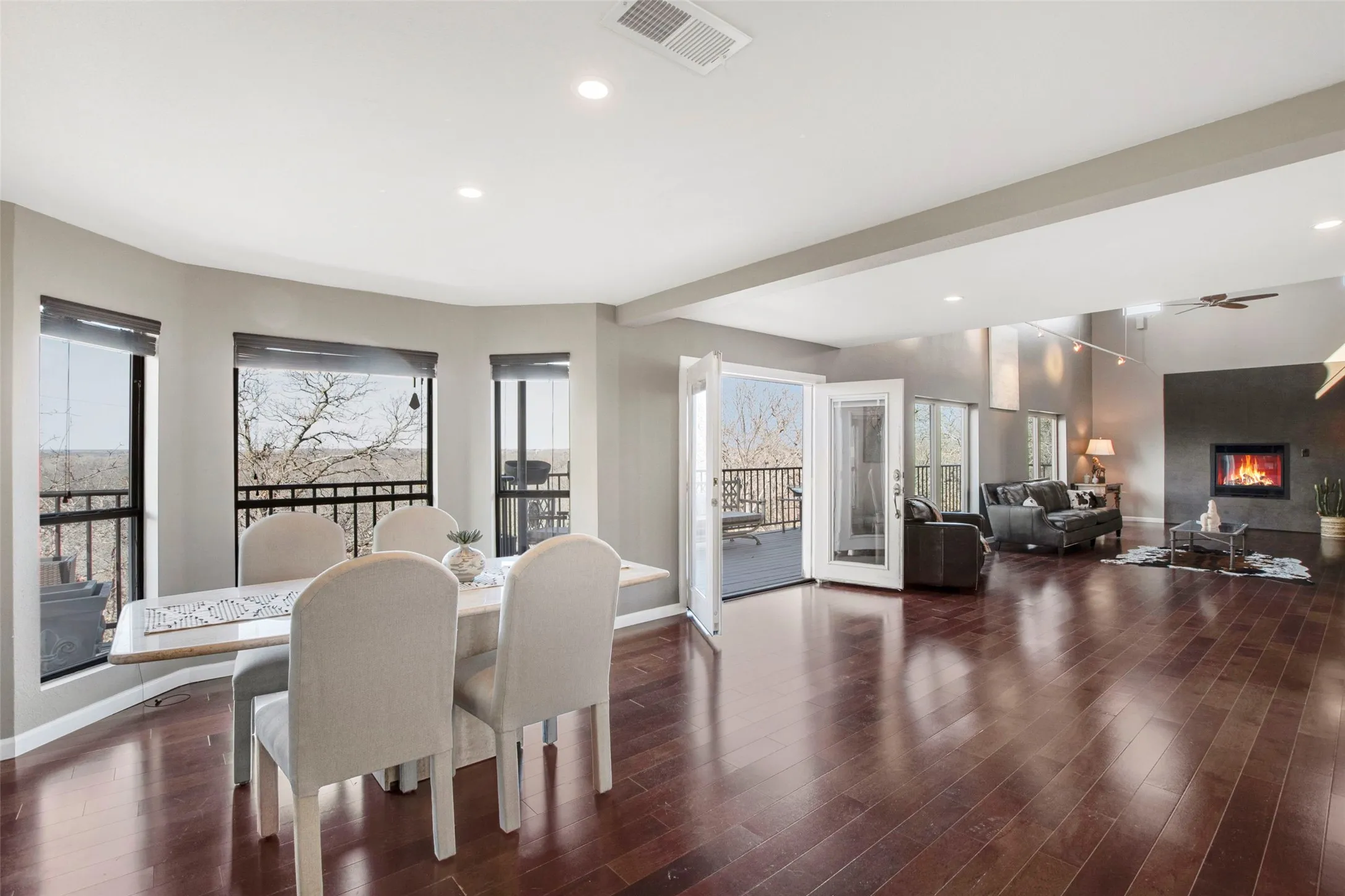 Open concept living space featuring rich wood-finish flooring, recessed lighting, and a prominent fireplace with a dark surround