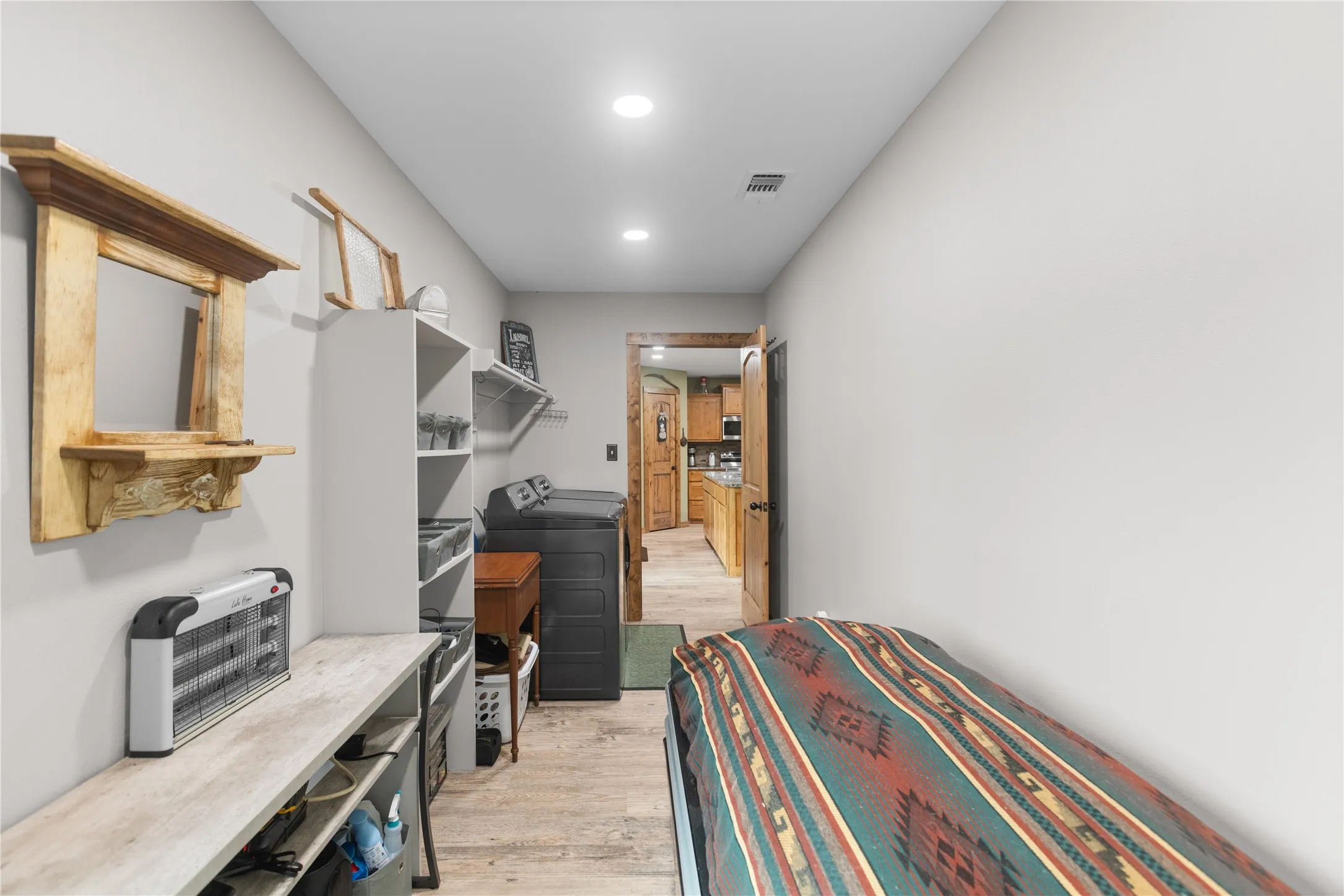 Laundry area with wood-finish flooring, recessed lighting, and wall-mounted shelving