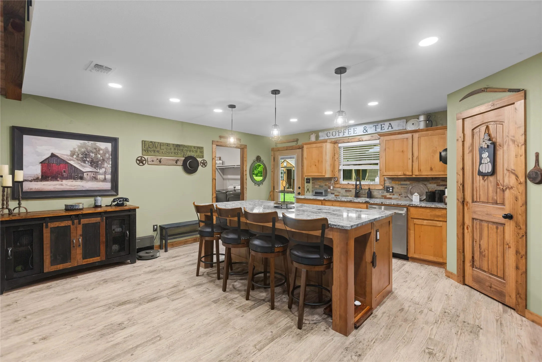 Open-concept kitchen featuring an island with seating, pendant lighting, recessed ceiling lights, wood-finish flooring, and natural wood cabinetry