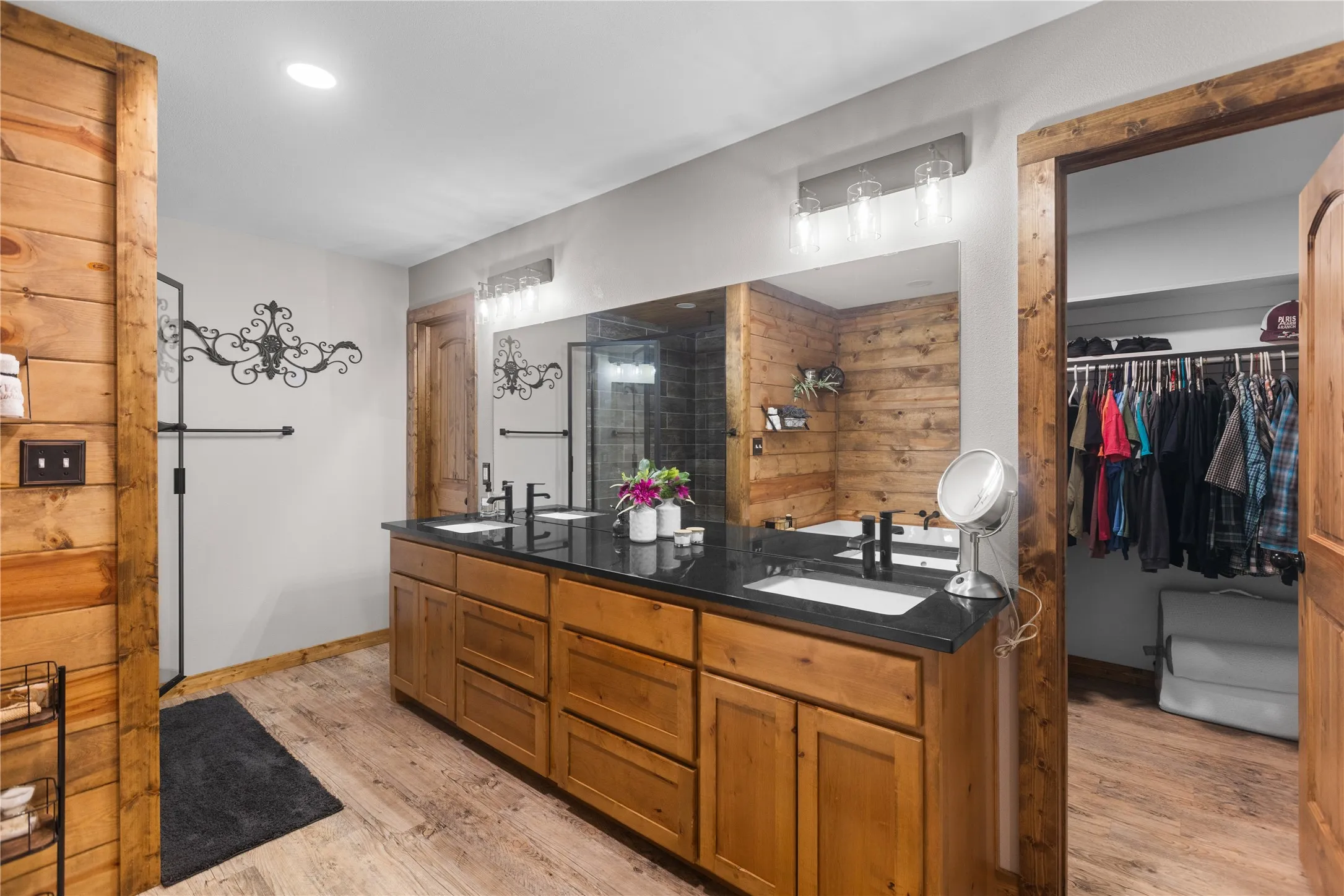 Double vanity with black countertop, wood-finish cabinetry, and black fixtures