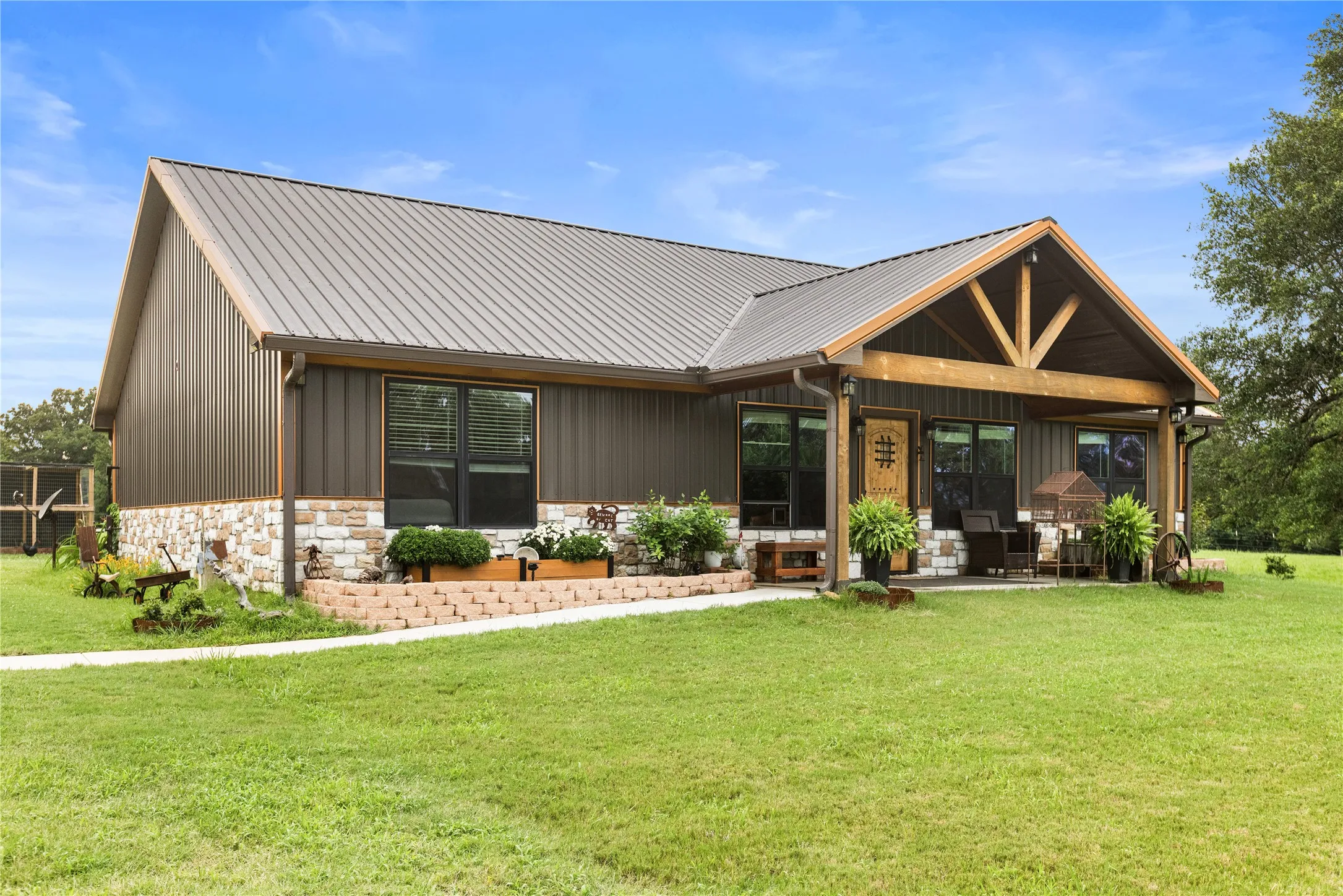 Ranch-style exterior featuring a metal roof, board and batten siding, and a stone facade