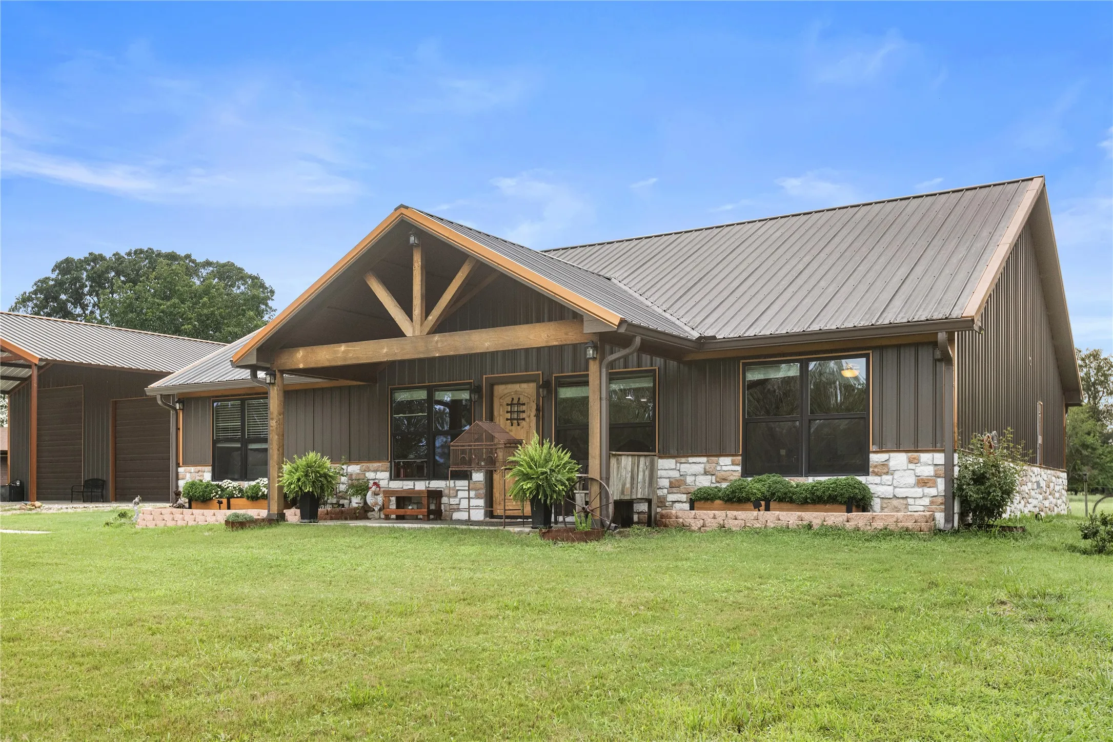 Contemporary exterior featuring a metal roof, board and batten siding, and a stone facade
