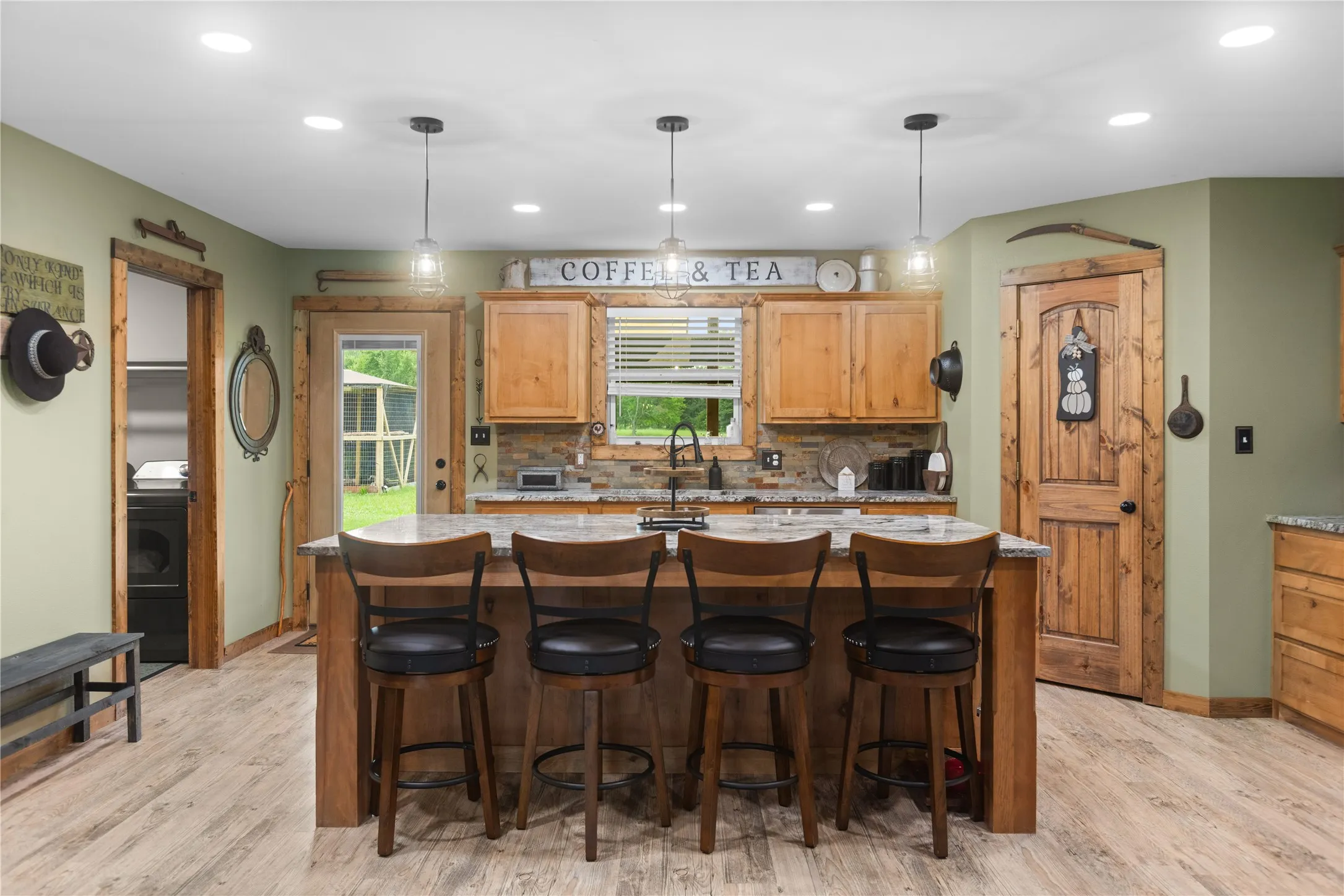 Central island with a granite countertop and seating, wood-finish flooring, natural wood cabinetry, recessed lighting, and pendant lighting fixtures