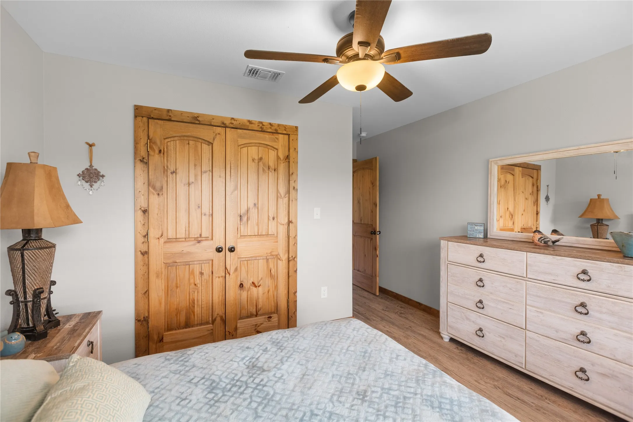 Interior room featuring light gray walls, wood-finish flooring, and a ceiling fan with integrated lighting