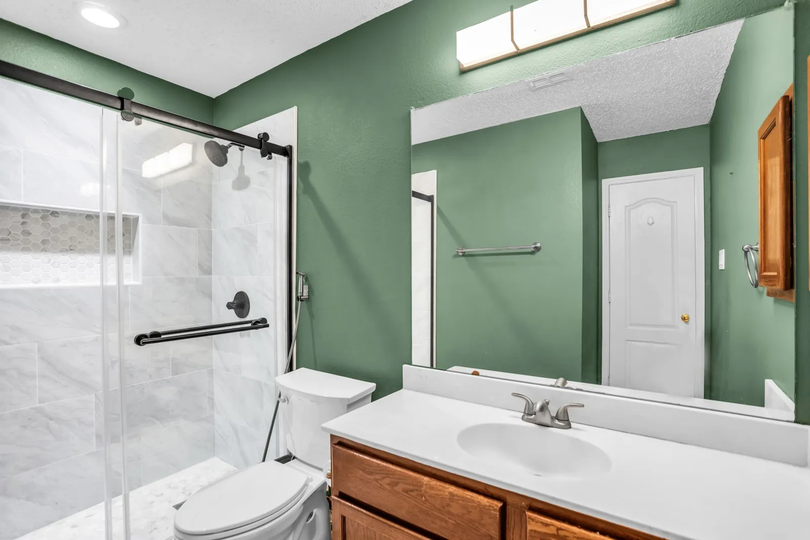 Contemporary bathroom featuring a glass-enclosed shower with matte black hardware, a tiled shower niche, and light-toned wall tile