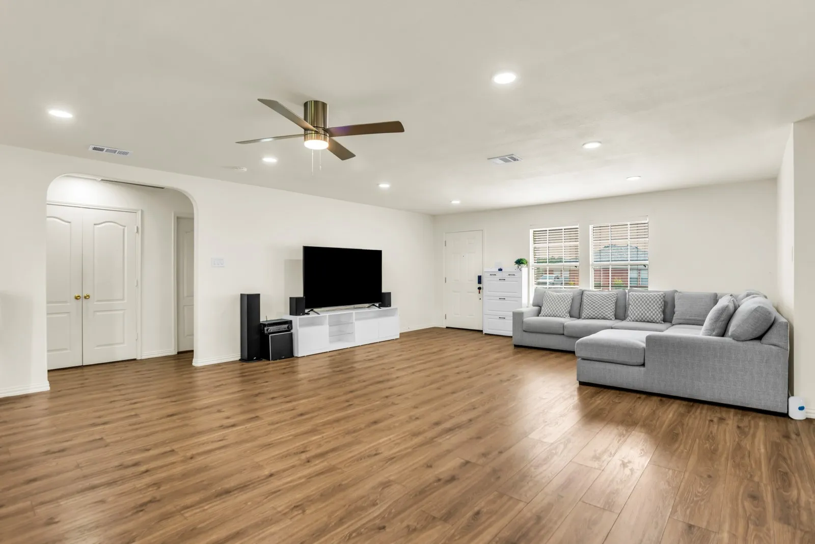 Spacious living area featuring wood-finish flooring, recessed lighting, and a ceiling fan
