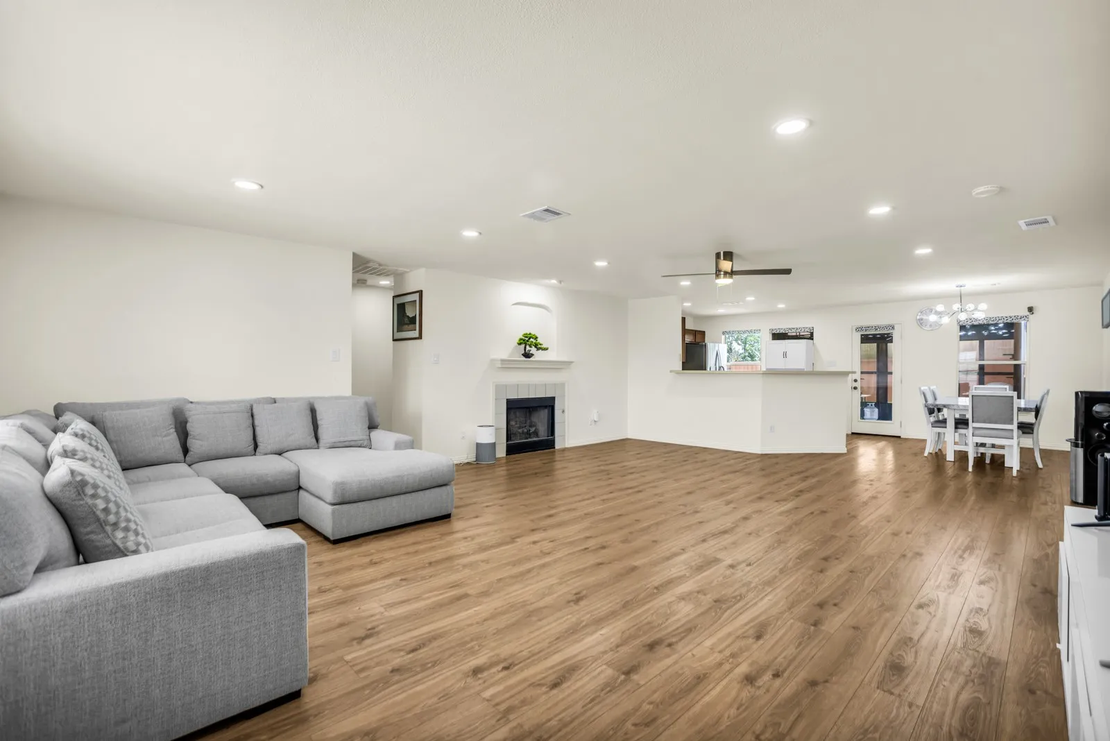 Open-concept living space featuring wood-finish flooring, recessed lighting, and a fireplace with a white mantel