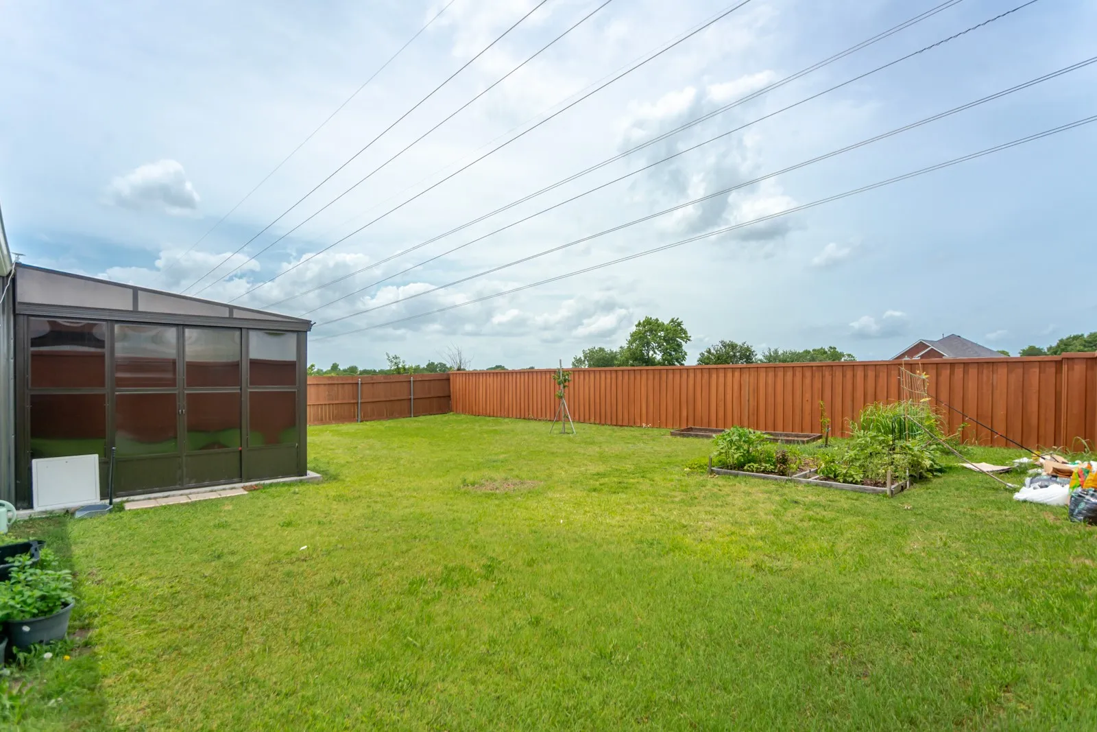 Expansive backyard featuring a manicured lawn, full privacy fencing, and two raised garden beds