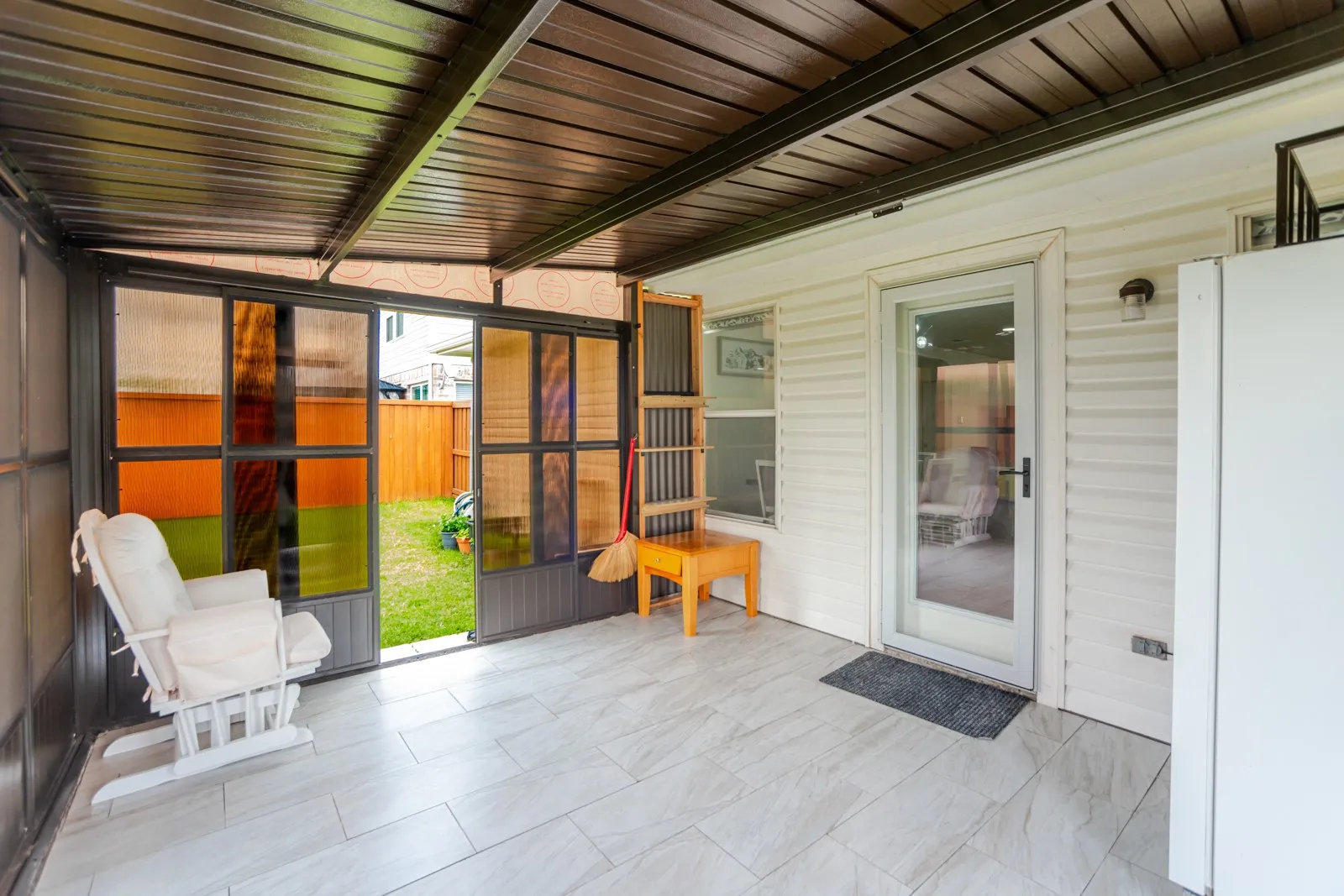 Enclosed patio featuring a dark metal roof, light-toned tile flooring, and a glass-paneled door