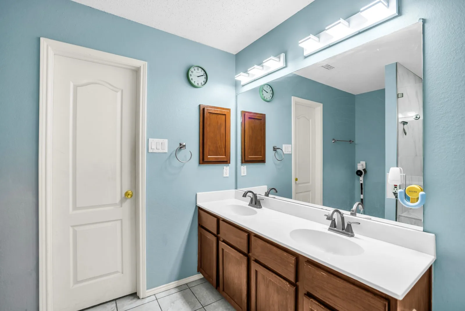 Double vanity featuring white countertops, dual undermount sinks, and wood-finish cabinetry