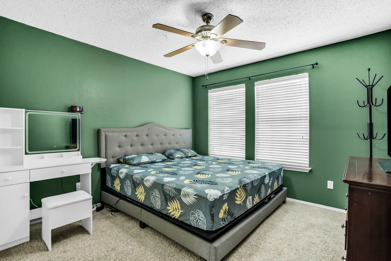 Carpeted bedroom featuring a ceiling fan with light fixture, dual windows with blinds, and a textured wall finish